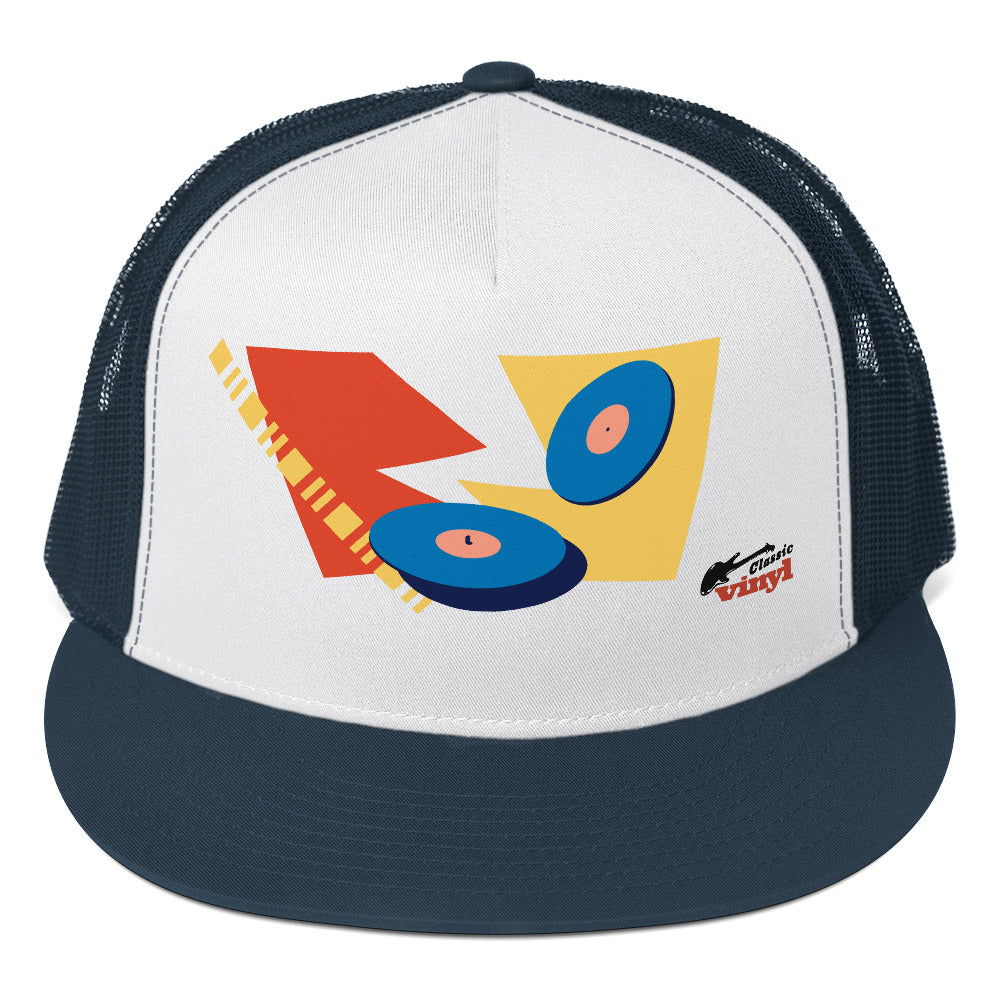 Front view of a navy and white trucker hat with a navy brim and mesh back. The white front panel features an abstract graphic of two blue vinyl records over red and yellow geometric shapes, with a small black guitar silhouette and red text reading 'Classic vinyl' in the bottom right corner.