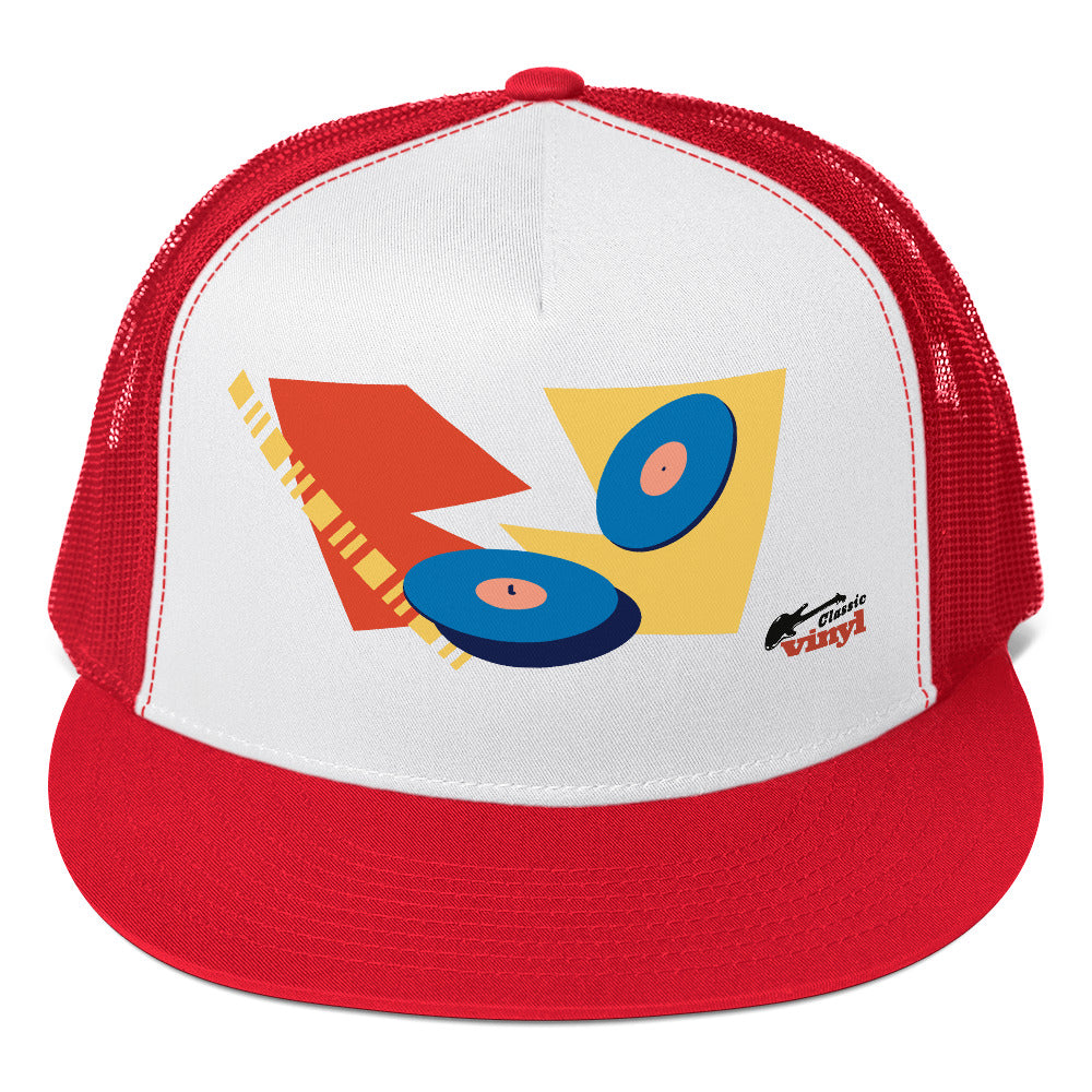 Front view of a red and white trucker hat with a red brim and mesh back. The white front panel displays an abstract design of two blue vinyl records layered over red and yellow geometric shapes, with the 'Classic vinyl' logo in black and red in the bottom right corner.