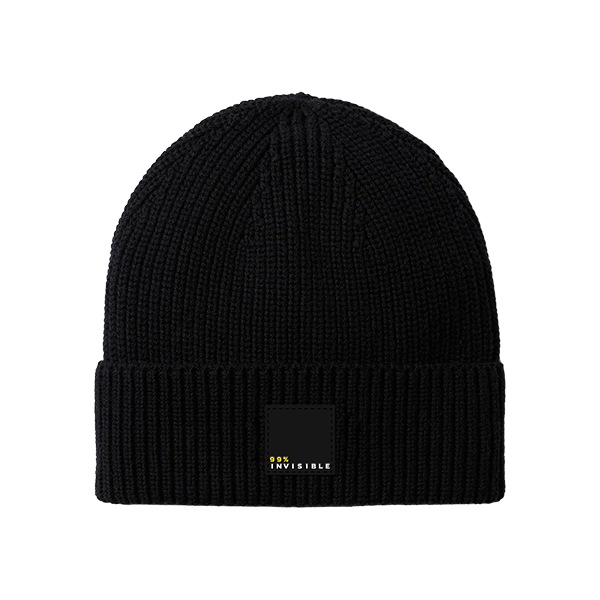 A black knit beanie with a folded cuff featuring a small rectangular patch that reads ‘99% Invisible’ in white and yellow text.