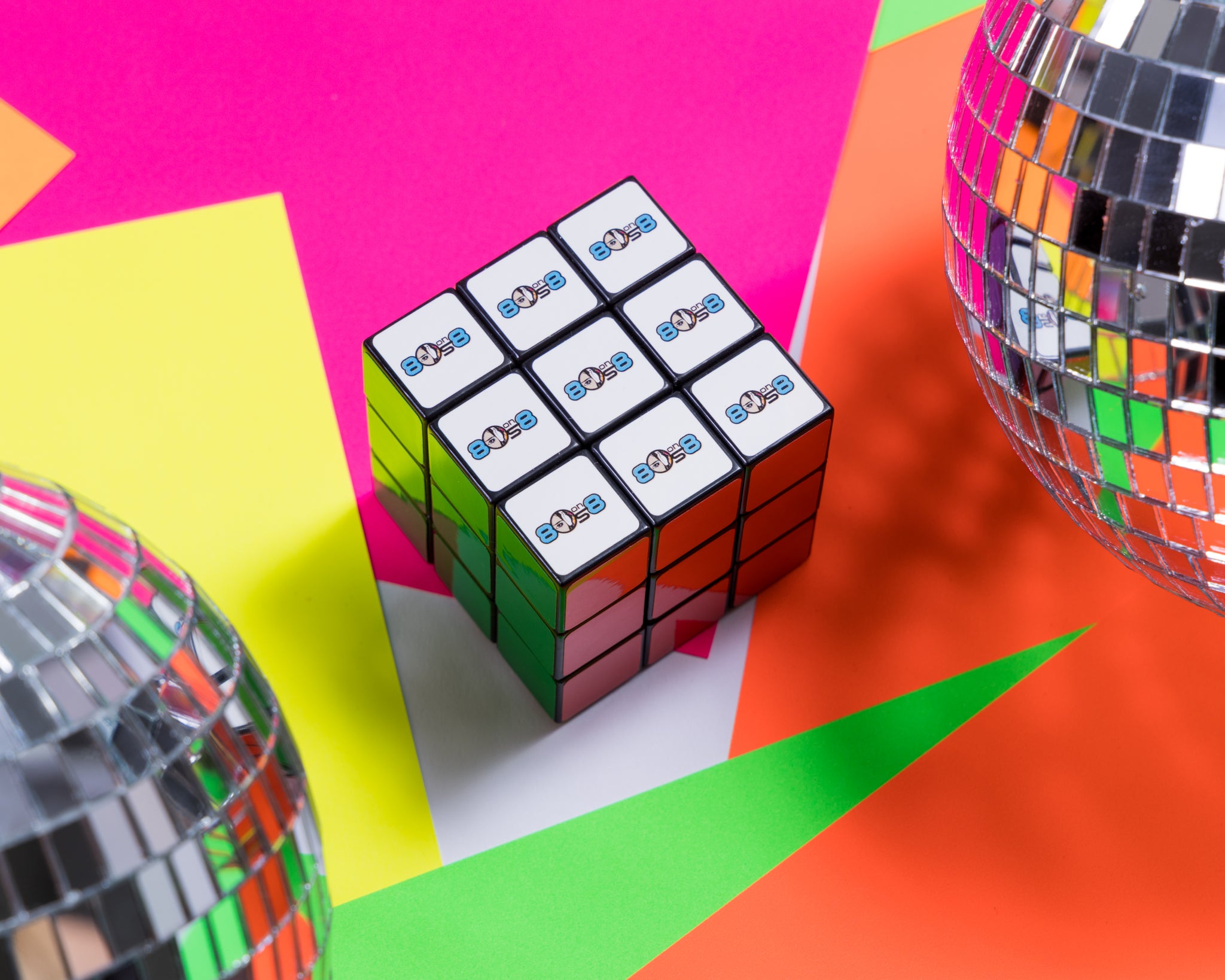 A colorful Rubik's cube with a logo featuring '80 on 8' on several sides.