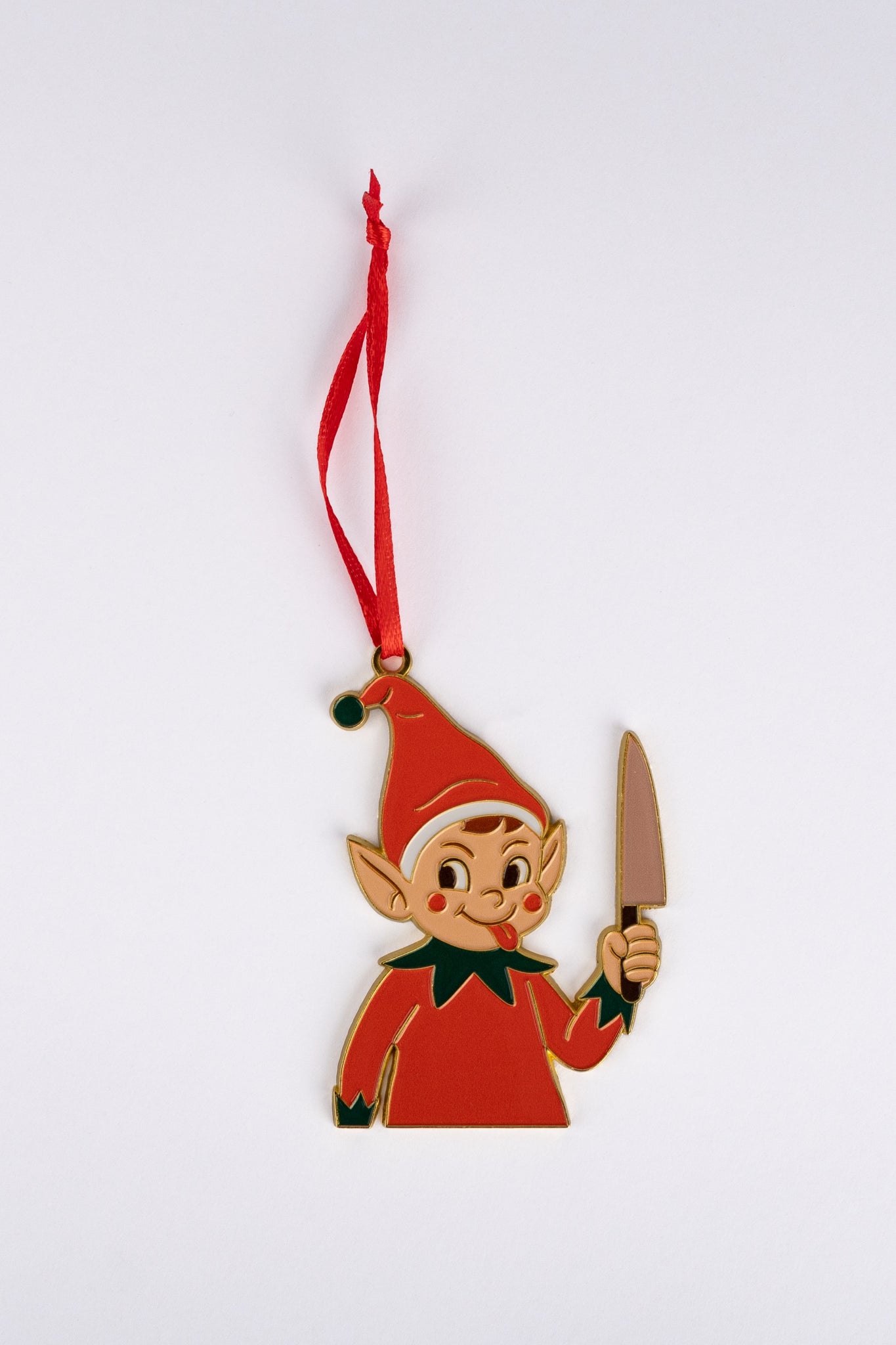 Ornament shaped like an elf wearing a red outfit and hat with green trim, sticking out its tongue and holding a silver knife, hanging from a red ribbon.