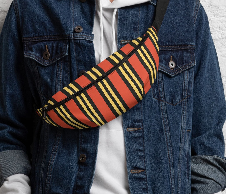 Close-up of a person wearing a denim jacket over a white hoodie with the orange, yellow, and black striped fanny pack worn crossbody across the chest.