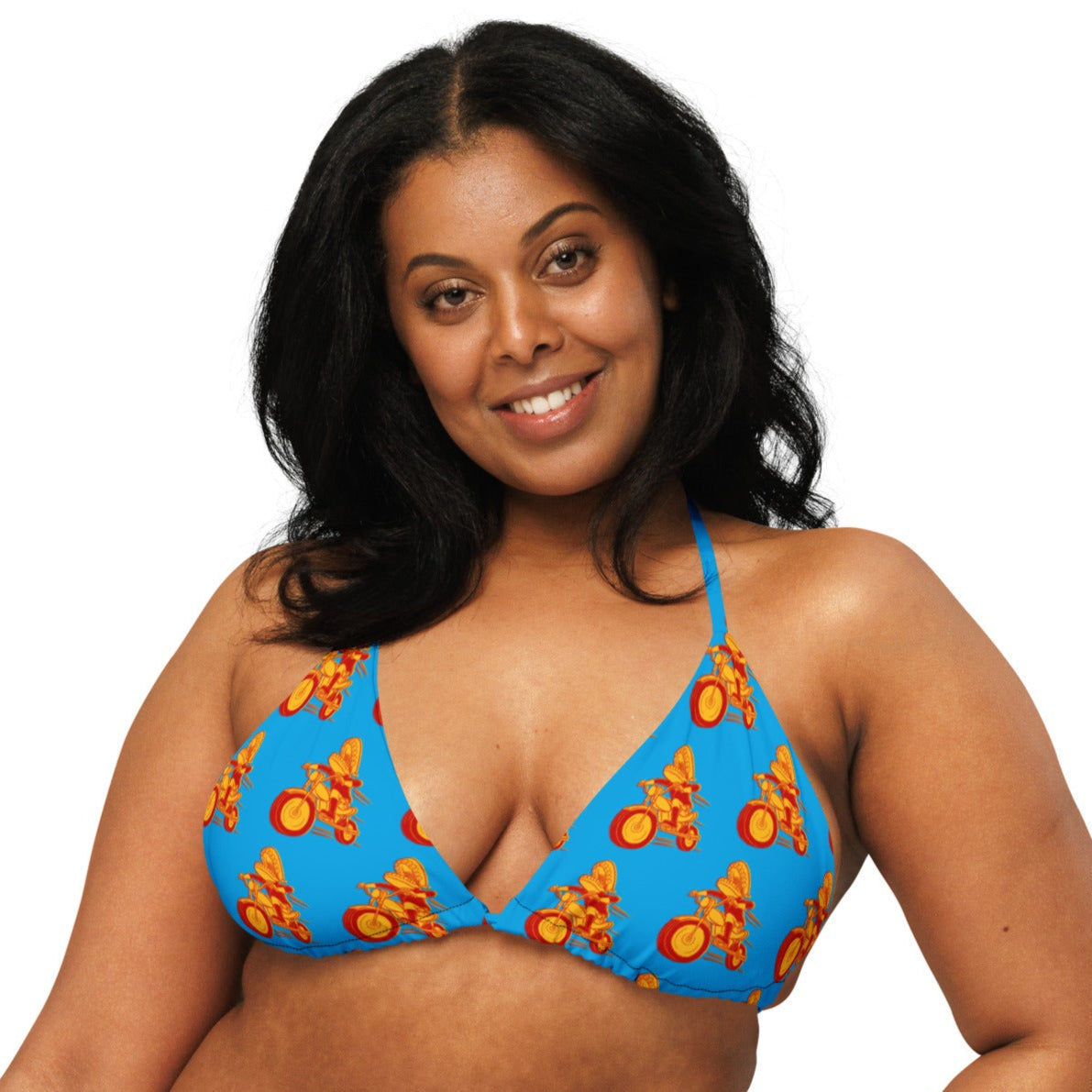 A woman wears a classic halter-style blue bikini top printed with a repeating pattern of red and yellow motorcycle characters, smiling against a white background.