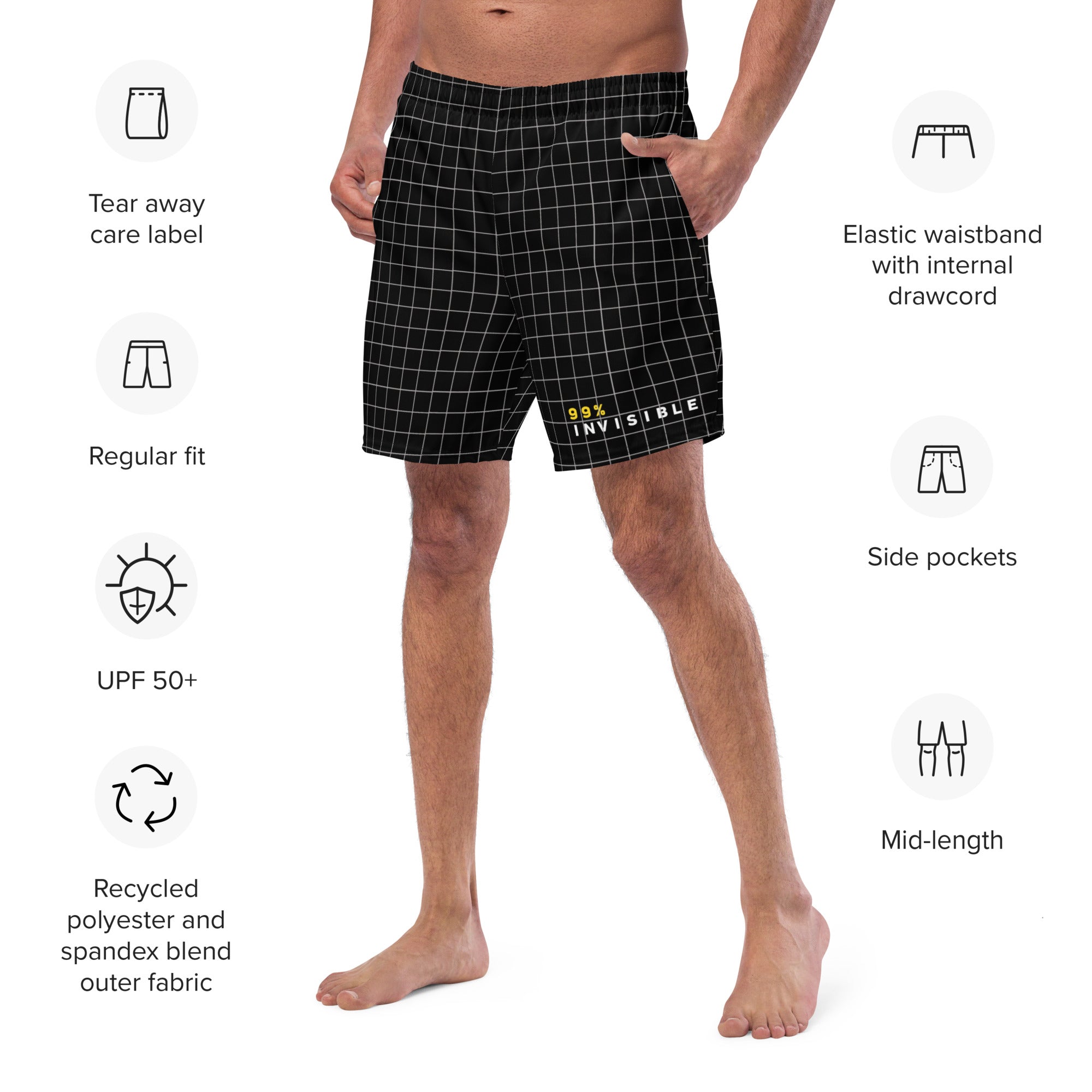 A man wears mid-length black grid-patterned swim trunks featuring the '99% INVISIBLE' text logo near the hem, surrounded by labeled icons highlighting features such as 'UPF 50+', 'Elastic waistband with drawcord', and 'Recycled polyester and spandex blend'.