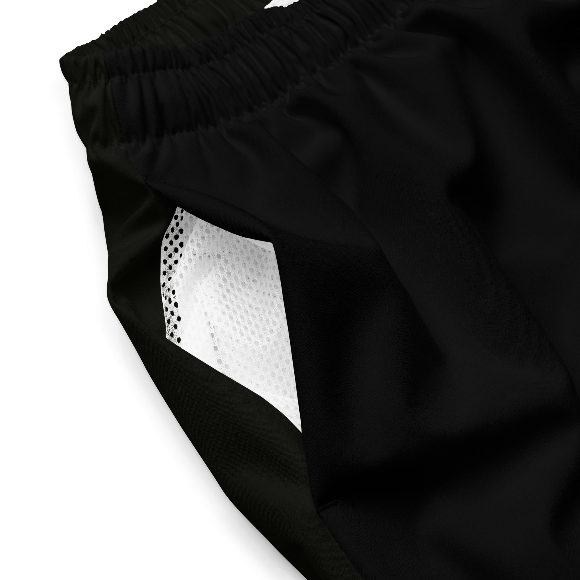A close-up of the side pocket of black swim trunks, showing the interior white mesh lining and gathered elastic waistband.