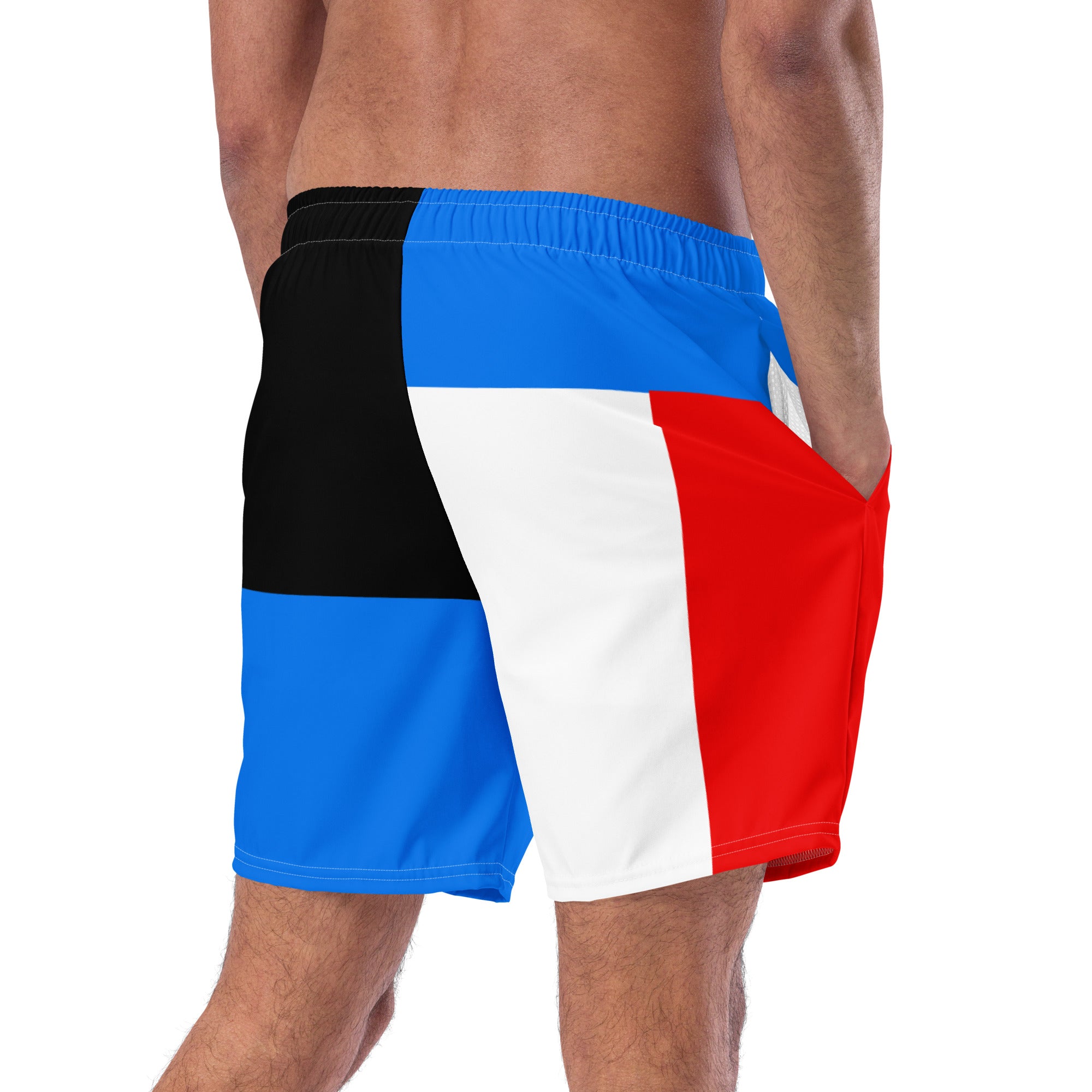A man shown from the waist down wearing color-blocked swim trunks with red, white, blue, and black panels, with his right hand in the side pocket.
