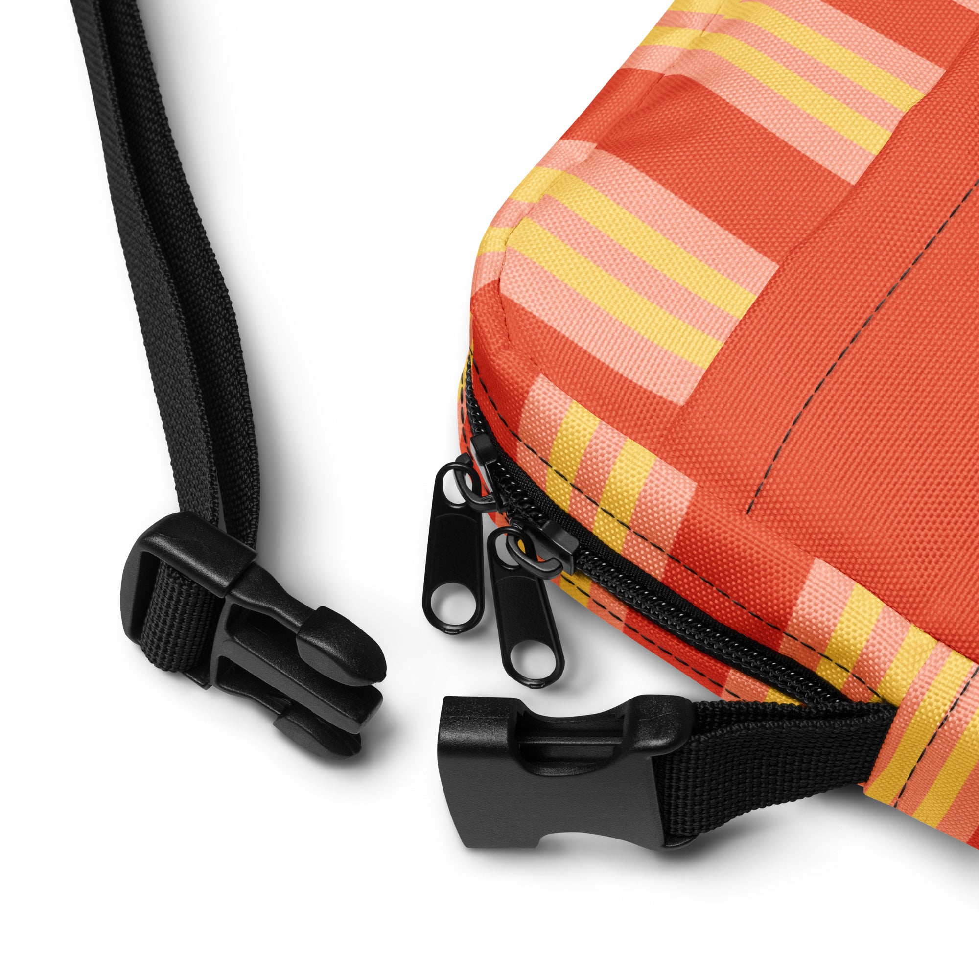 Close-up of the corner of the orange crossbody bag showing black zippers, adjustable plastic clips, and the striped yellow and pink fabric detail.