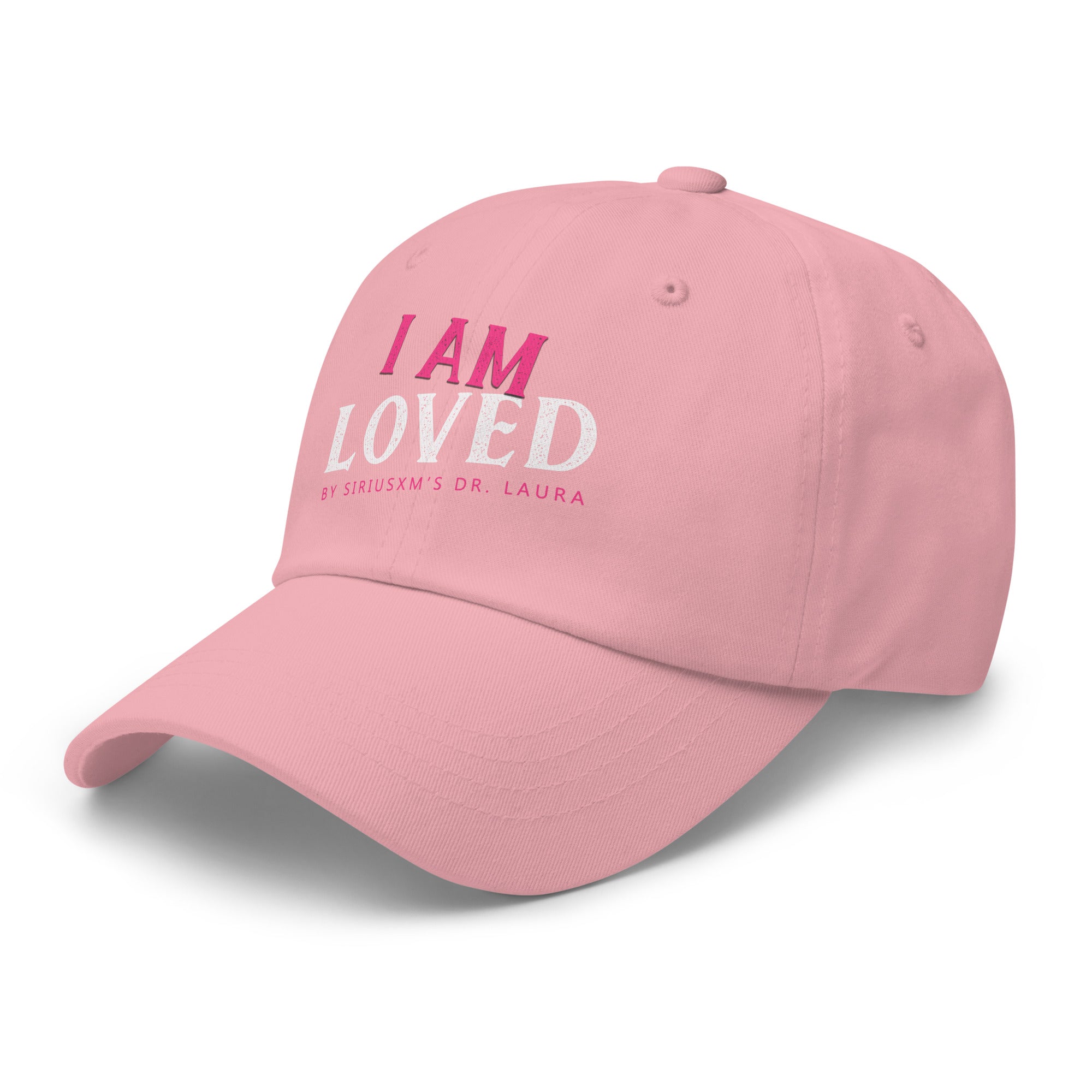 A pink classic dad hat shown from a side angle, featuring the text 'I AM LOVED' on the front. The words 'I AM' are in pink, 'LOVED' in textured white, and 'BY SIRIUSXM’S DR. LAURA' is written in small pink lettering beneath.