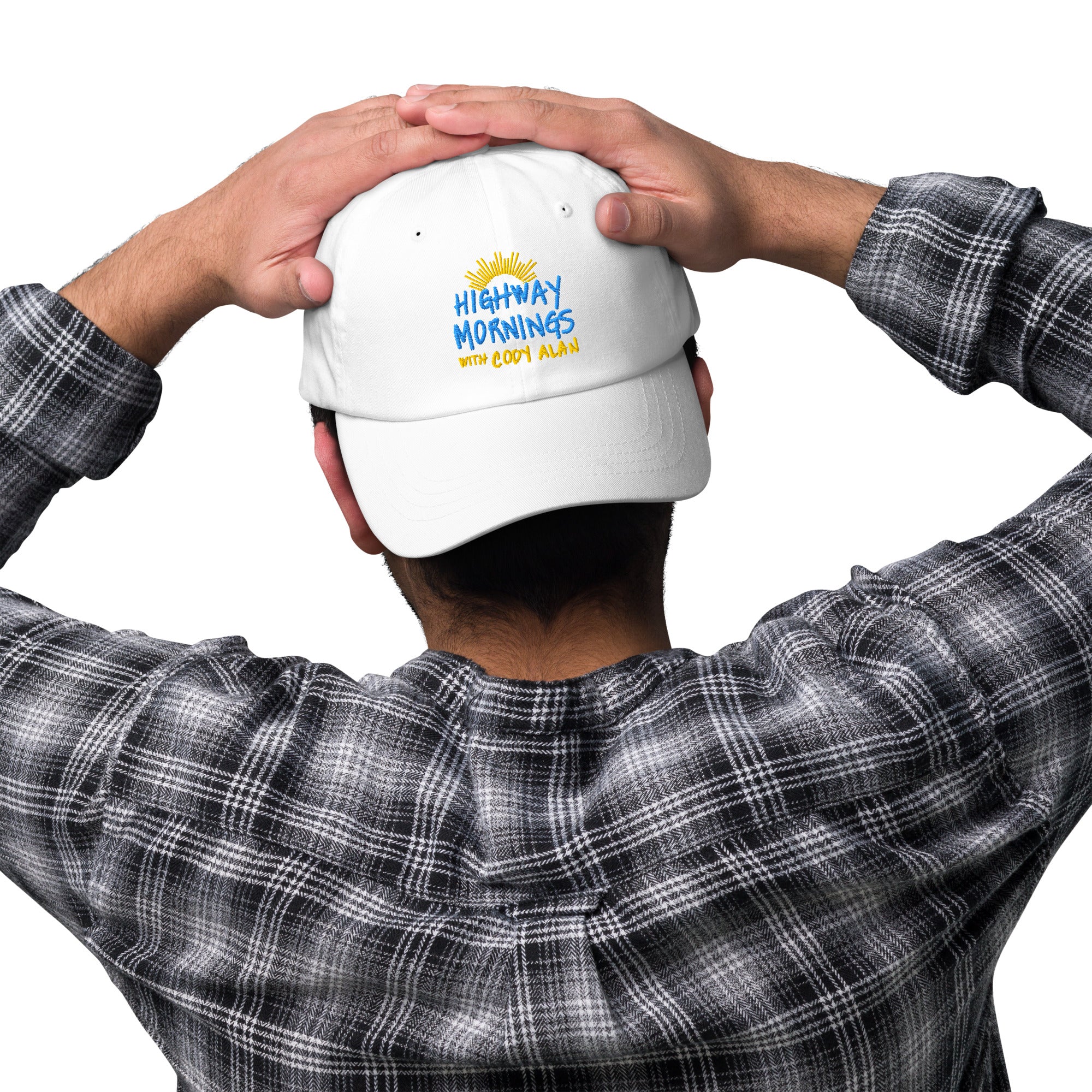A man seen from behind with his hands resting on his head, wearing a white dad hat with the embroidered text 'HIGHWAY MORNINGS WITH CODY ALAN' and a sunburst design above the lettering.