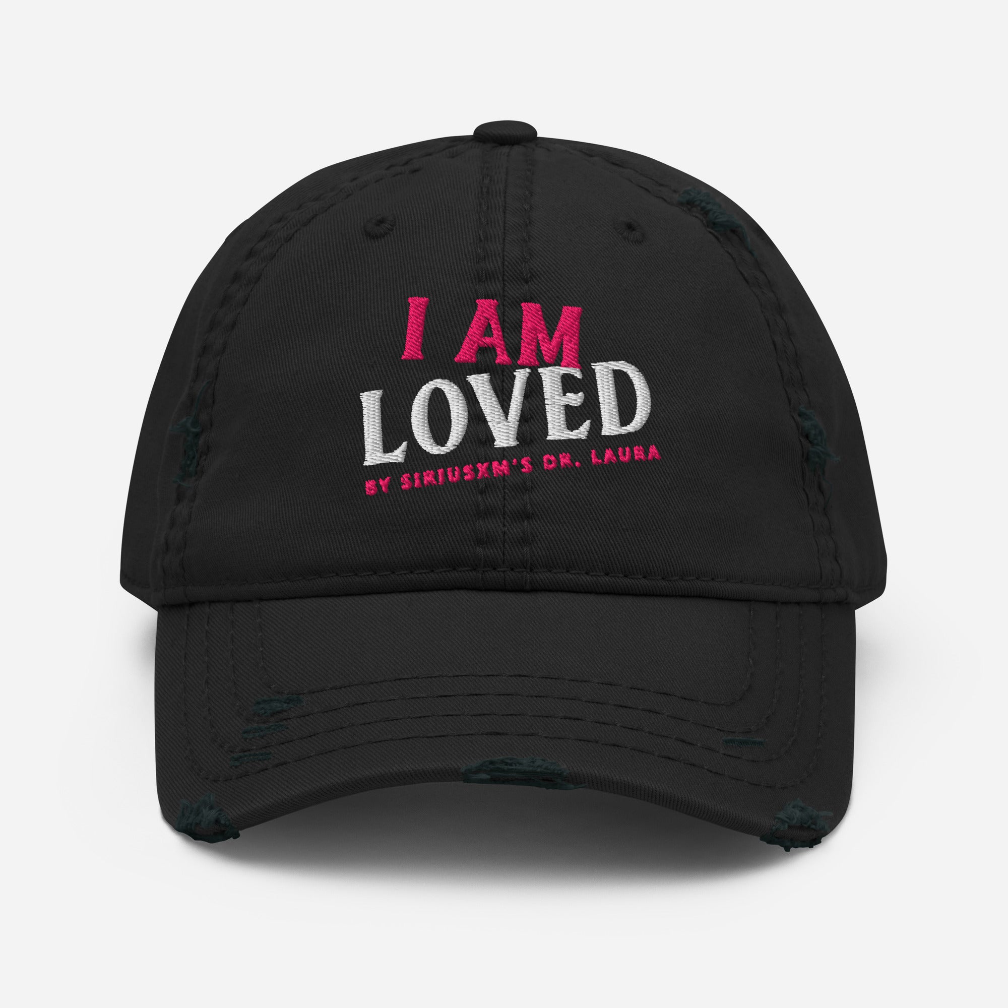 Black baseball cap with distress marks on the front edge of the bill. The text on the front of hat reads 'I AM LOVED,' with 'I AM' in pink and 'LOVED' in white textured lettering. Below, it says 'BY SIRIUSXM'S DR. LAURA' in smaller pink text.