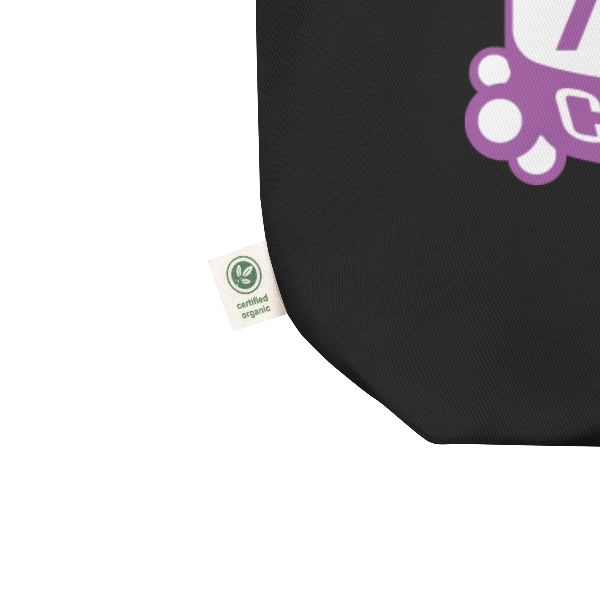 Close up of bottom left corner of black tote featuring the small manufacturer's tag reading 'certified organic' in reference to the canvas fabric.