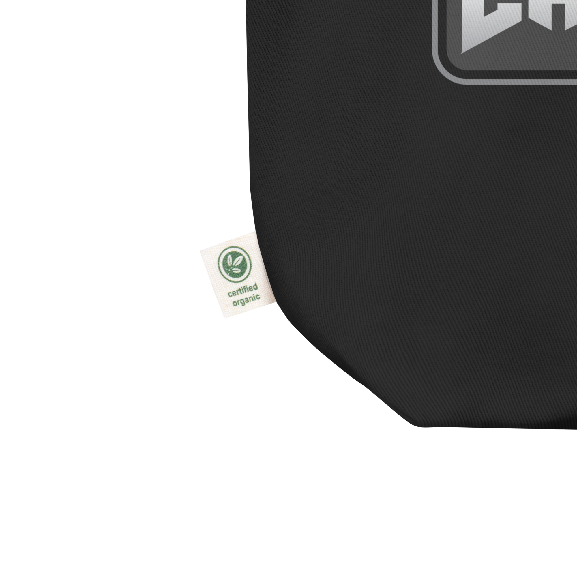 Close up of tote bag's lower left corner featuring manufacturer's tag that confirms canvas fabric is 'certified organic.'