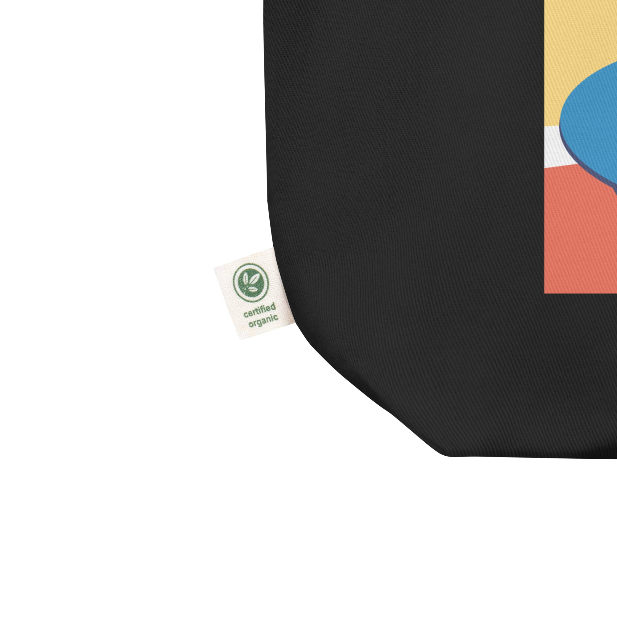 Close-up of the bottom corner of a black tote bag showing a white fabric tag with a green circular icon and the text 'certified organic.'