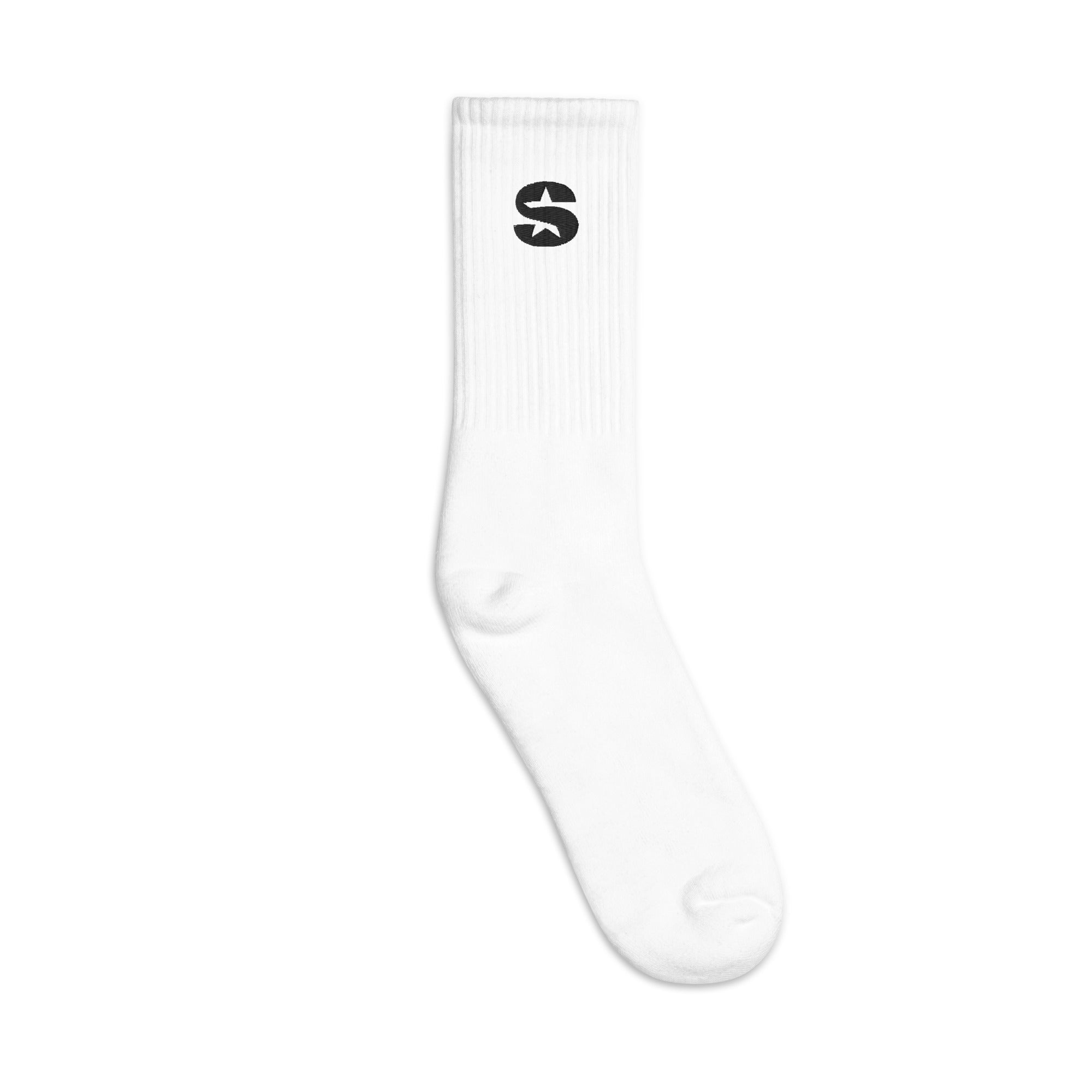 A white crew sock with a ribbed upper section. The socks features a bold black "S" logo with a star incorporated into the design on the outer side of the sock. The sock has a classic, minimalistic design with a snug fit around the calf and is against a white background.