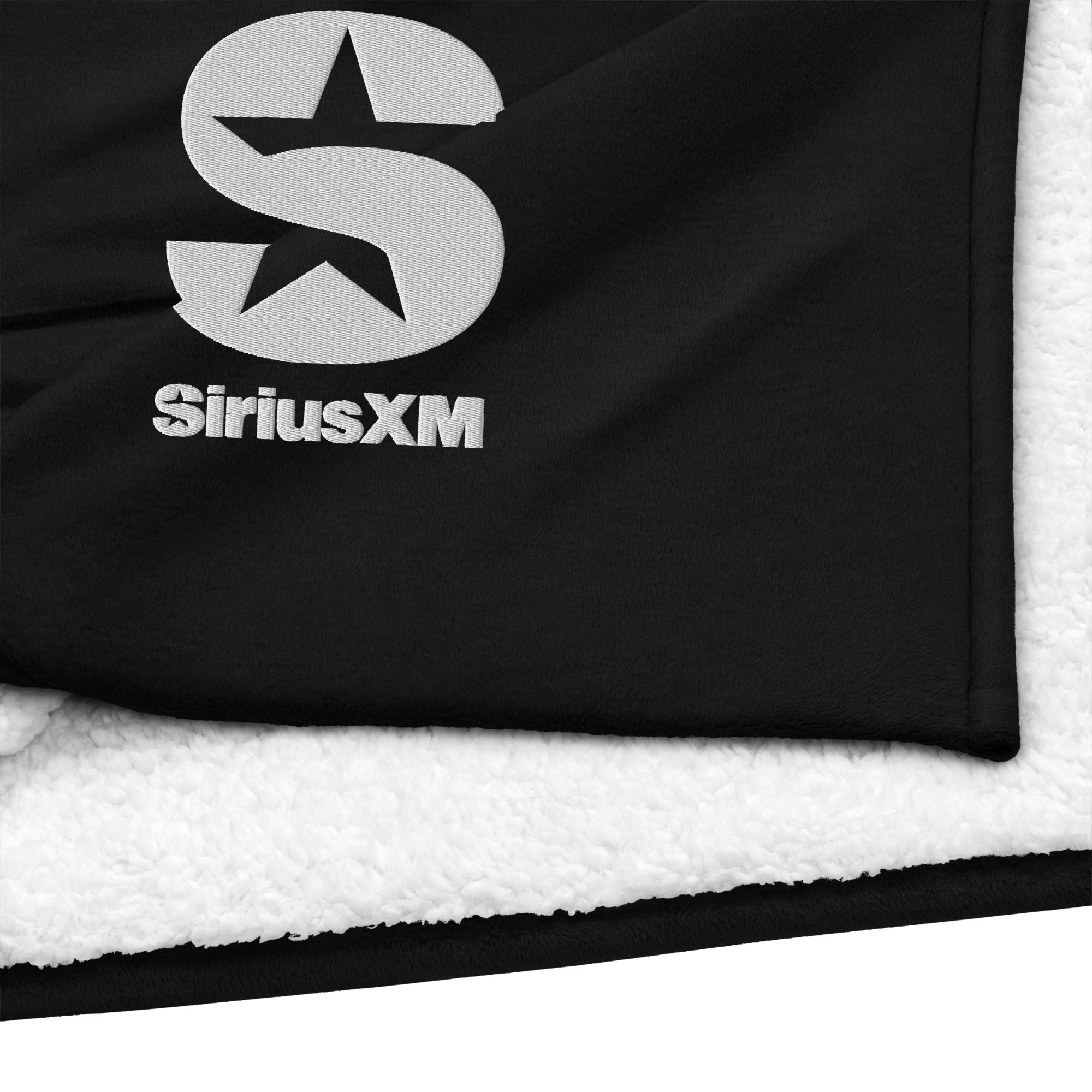 Black blanket featuring the 'SiriusXM' logo and a star design. Soft white backing visible.