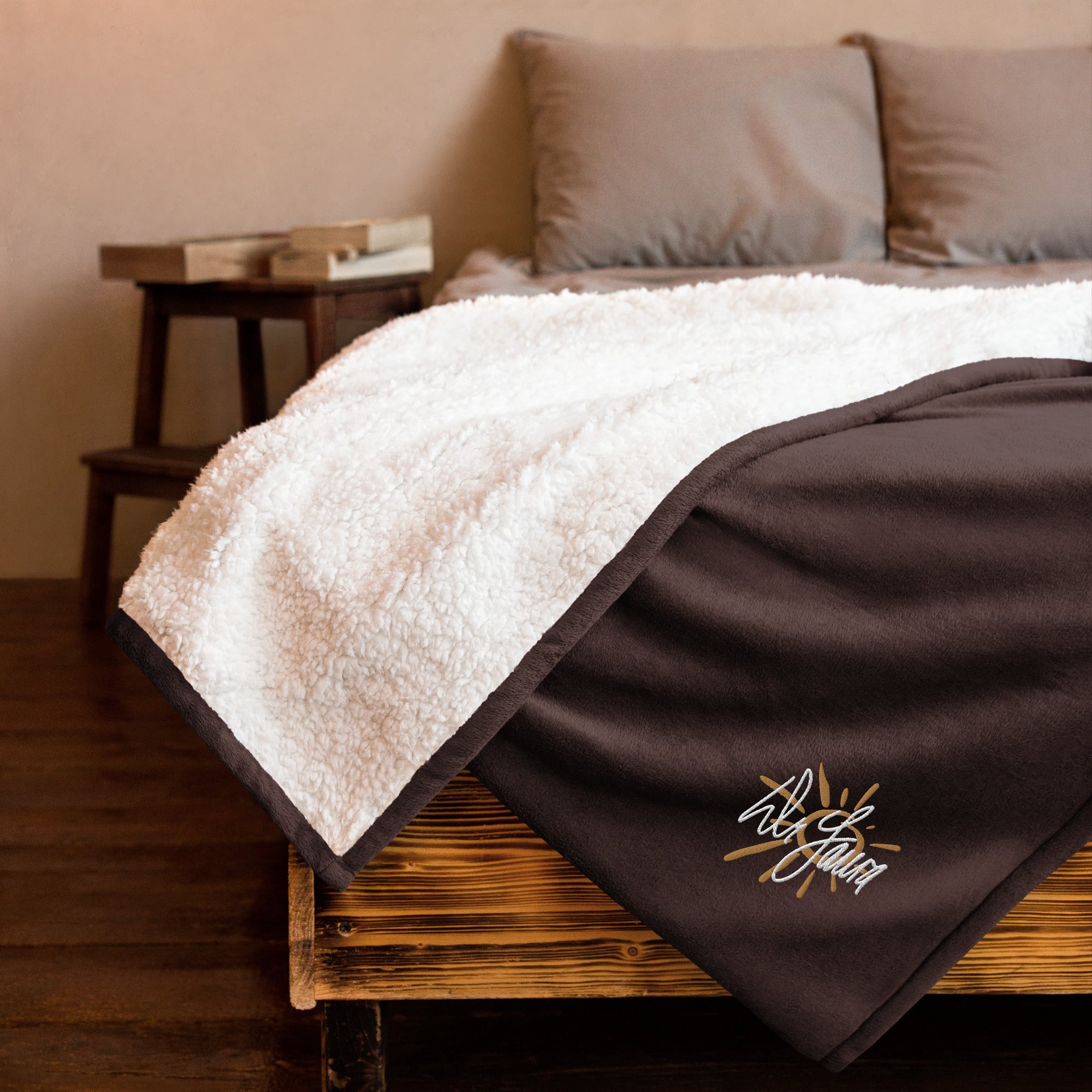 Cozy blanket with a fluffy white top and a dark brown bottom featuring the 'Dr. Laura' signature logo in the corner, elegantly draped on a bed.