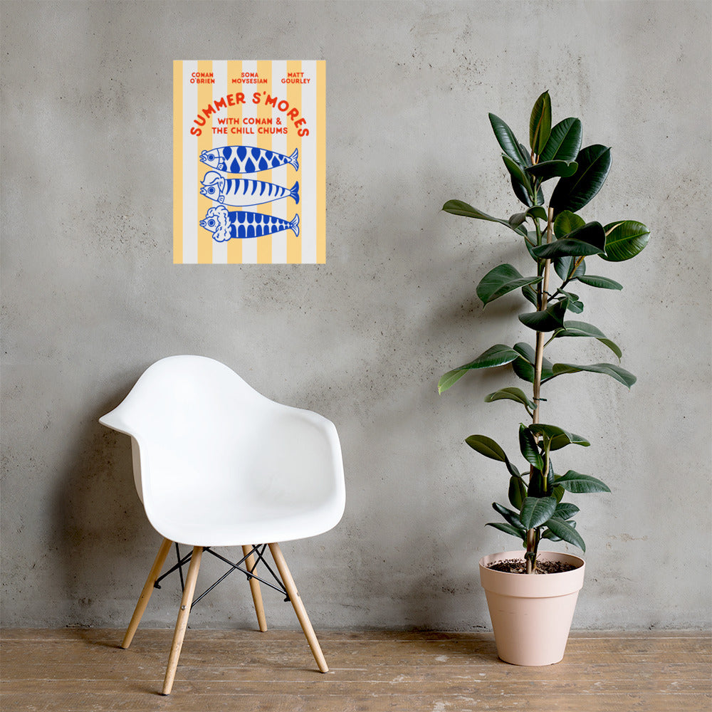 A 'Summer S’mores with Conan & the Chill Chums' poster is displayed on a gray concrete wall above a modern white chair and next to a tall potted rubber plant in a minimalist room.