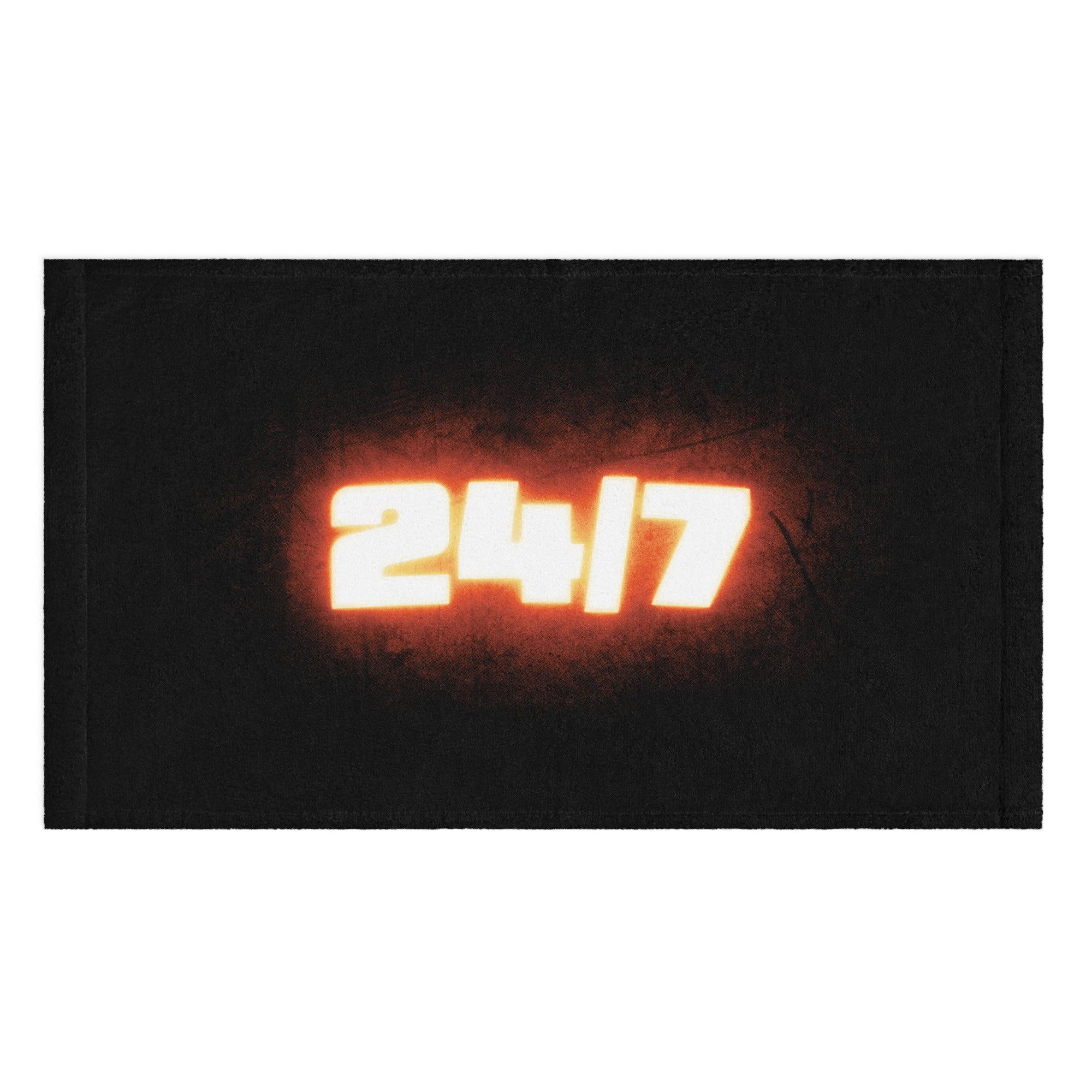 Front view of a black rally towel featuring a large glowing '24/7' design in bold white numbers with a fiery orange haze around the text, centered on the towel.