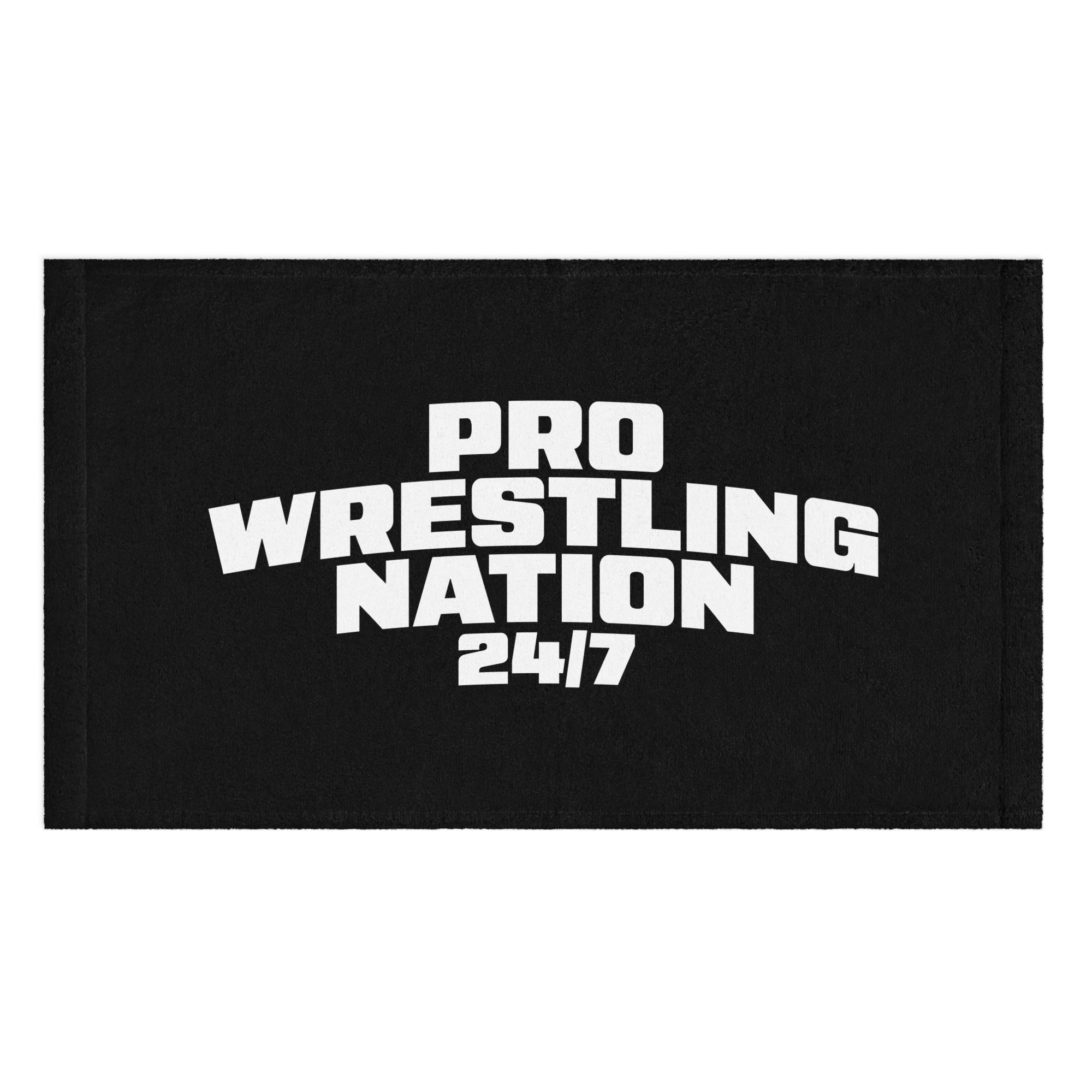Flat lay of a black rally towel printed with bold white text that reads 'PRO WRESTLING NATION 24/7' in a blocky arched style across the center.