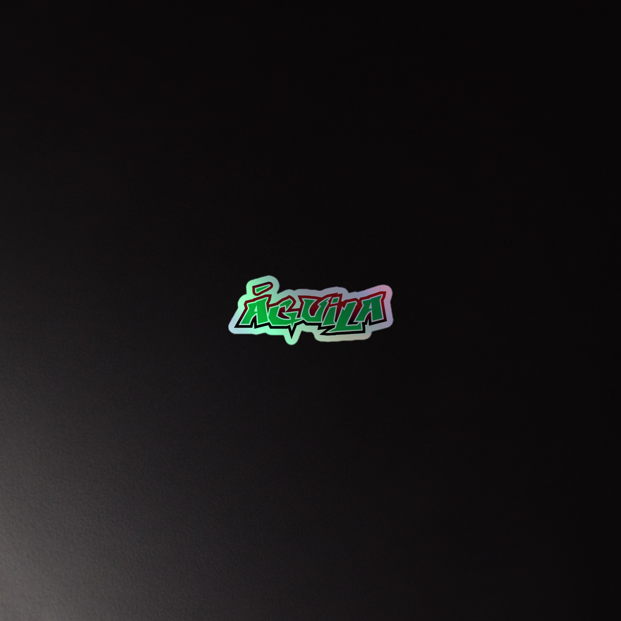 Holographic sticker of the 'Águila' logo in colorful, graffiti-style lettering on a black background.