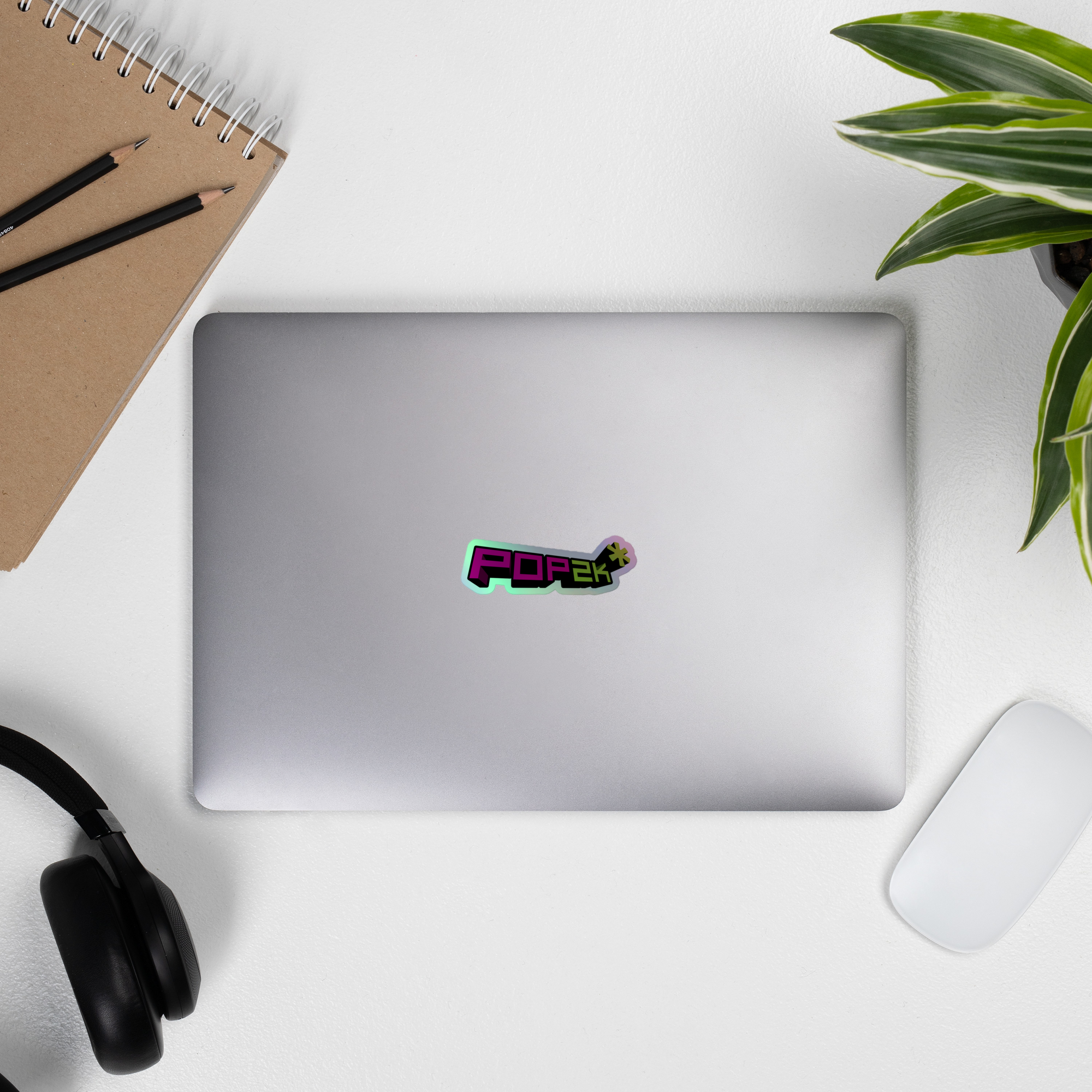Laptop displaying a colorful 'POP2k' holographi sticker on top.