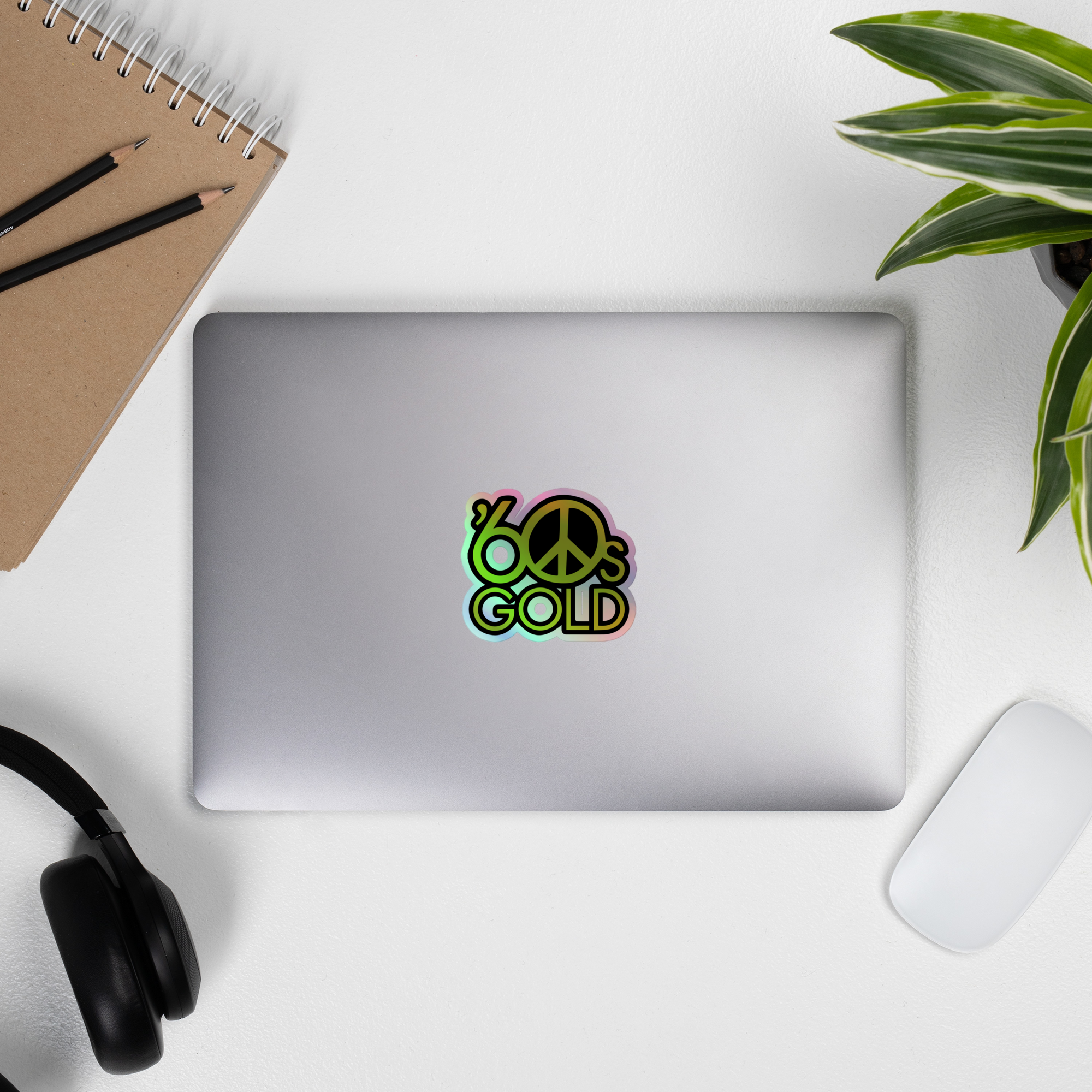 Laptop displaying a colorful '60s GOLD' holographic sticker.