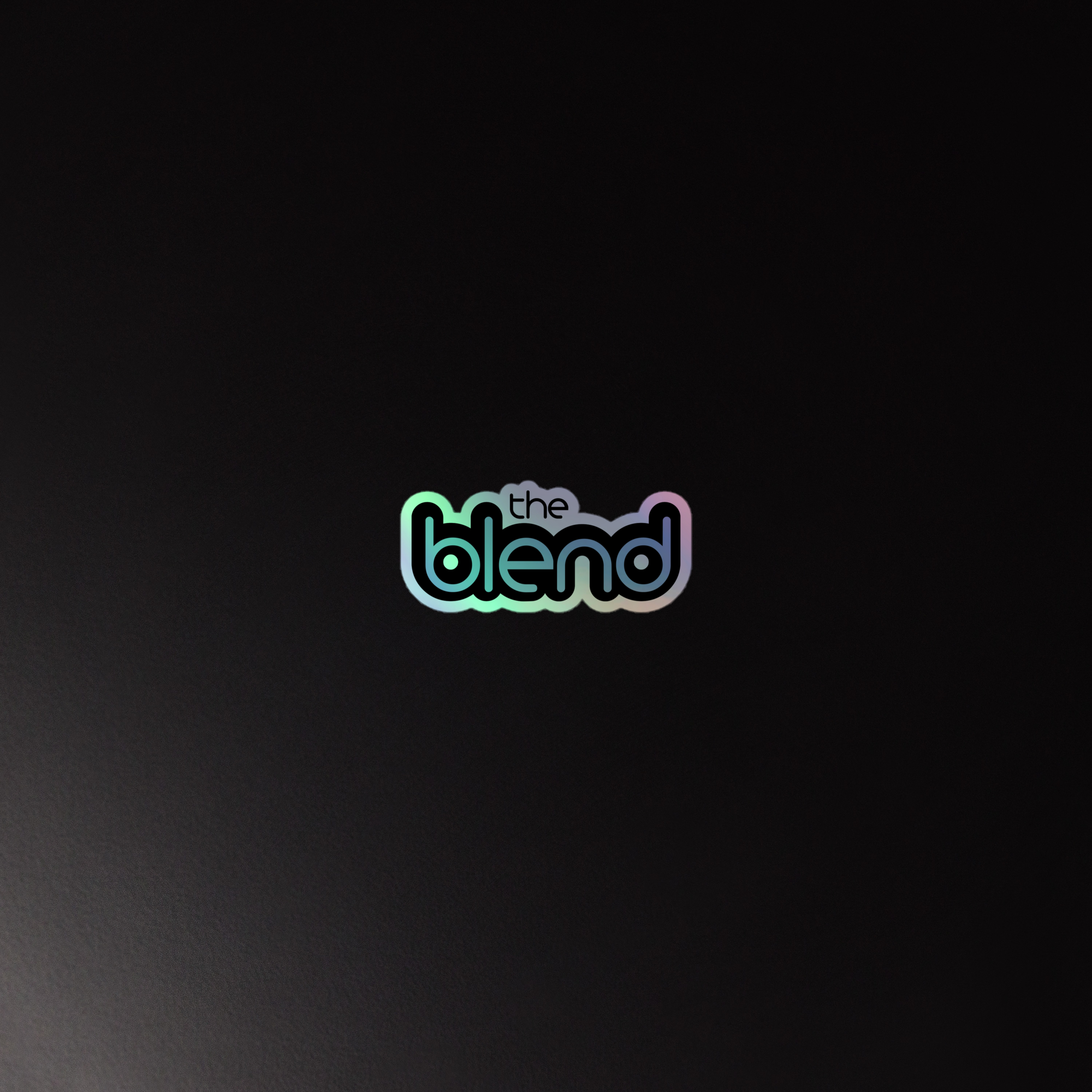 Colorful holographic sticker of the 'the blend' logo on a dark background.
