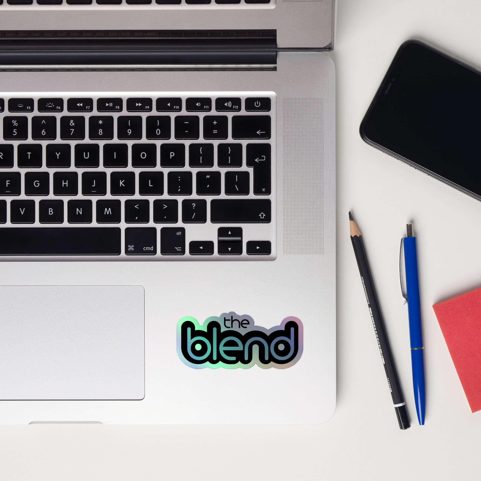 A laptop keyboard displaying a 'the blend' holographic sticker.