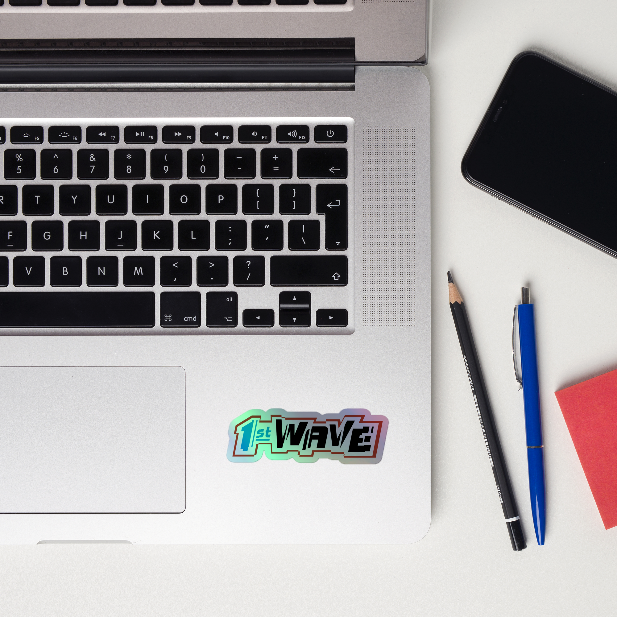 A close-up of a laptop keyboard displaying a colorful '1st WAVE!' holographic sticker.