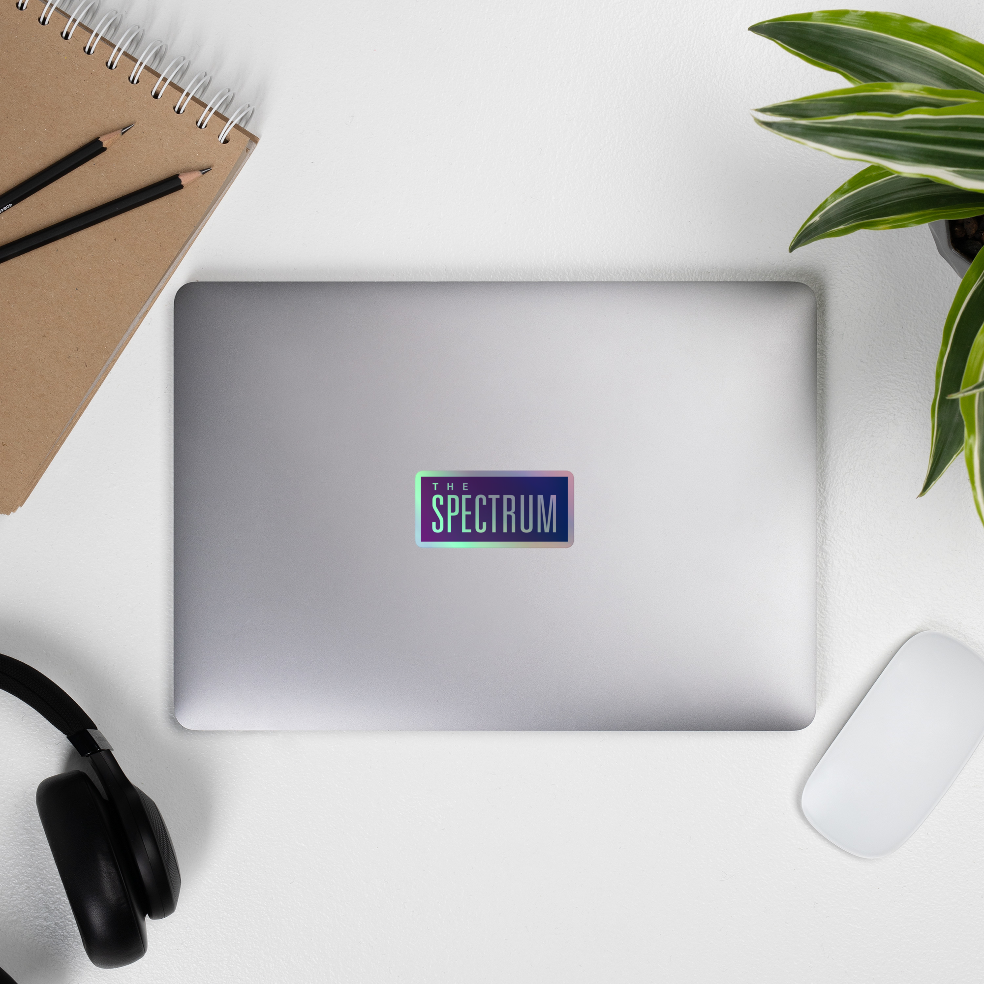 Top-down view of a laptop displaying 'THE SPECTRUM' holographic sticker.