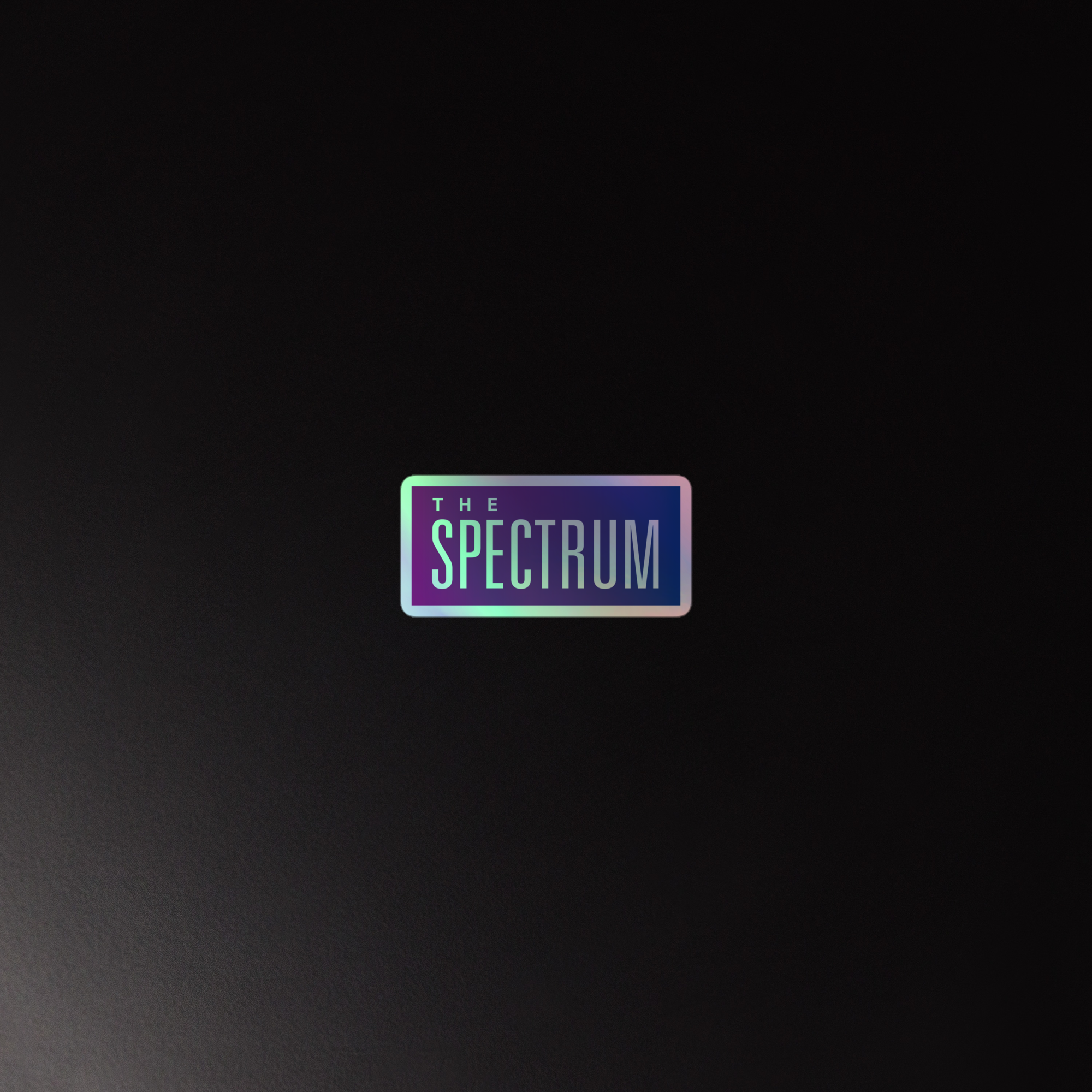 Holographic sticker of  the 'The Spectrum' logo on a dark background.