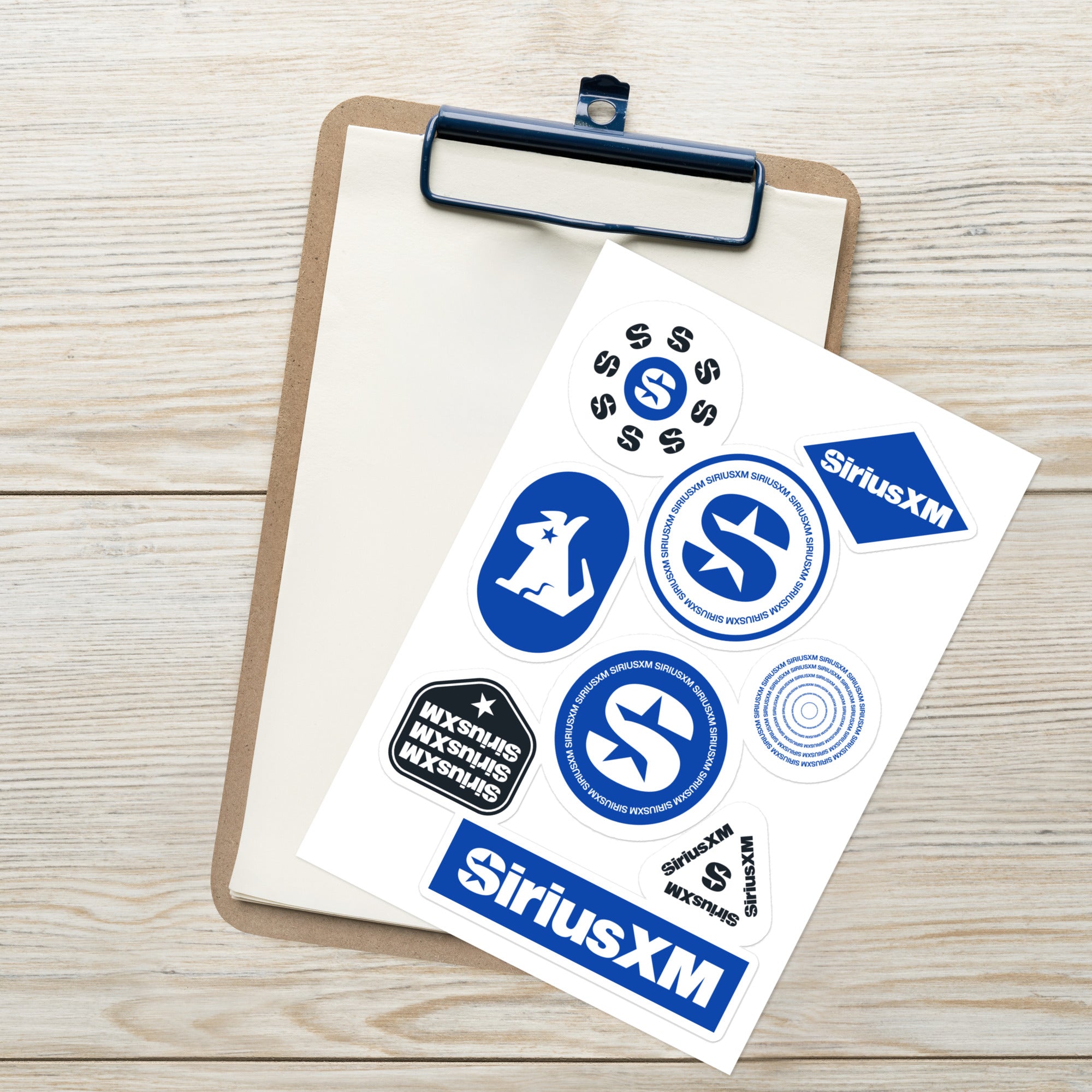 Sticker sheet featuring 8 'SiriusXM' logos in various designs on a clipboard against a wooden background.