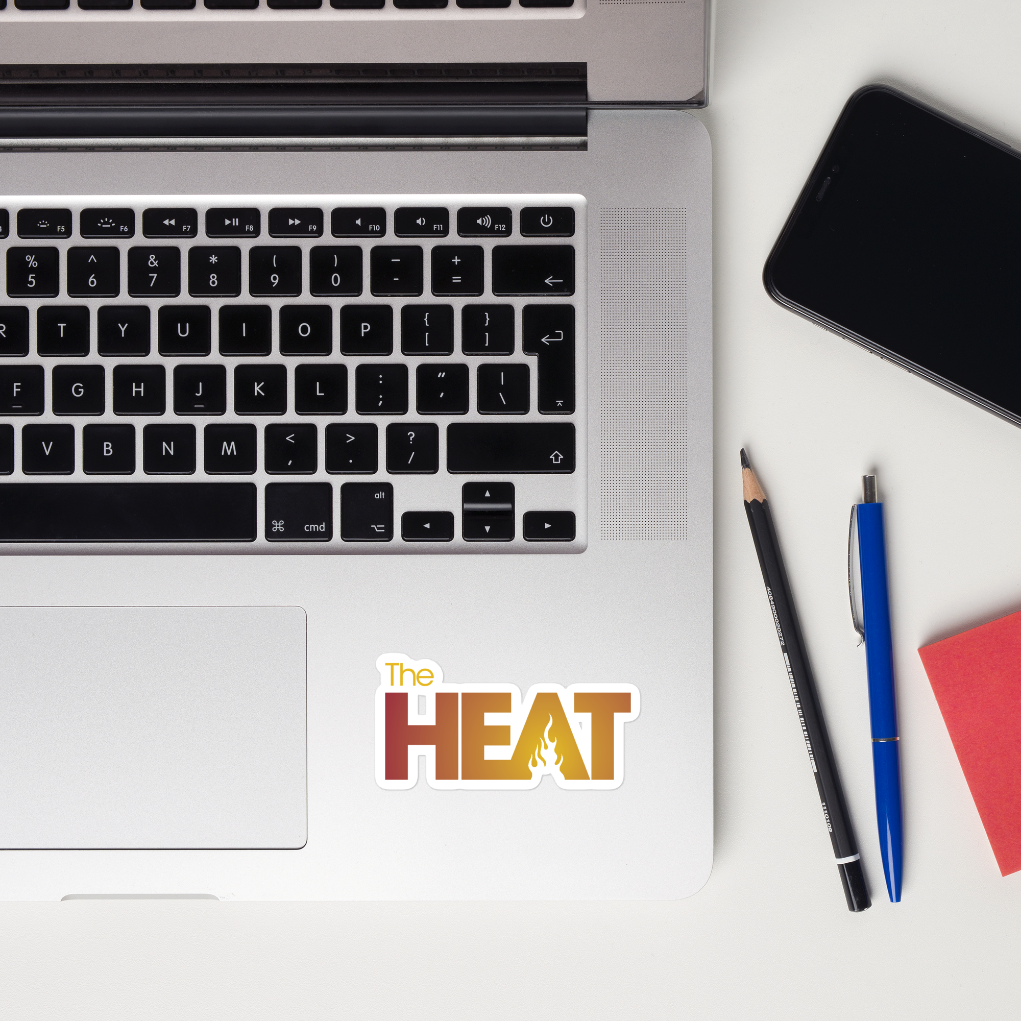 Top view of a laptop keyboard displaying a 'The HEAT' sticker.