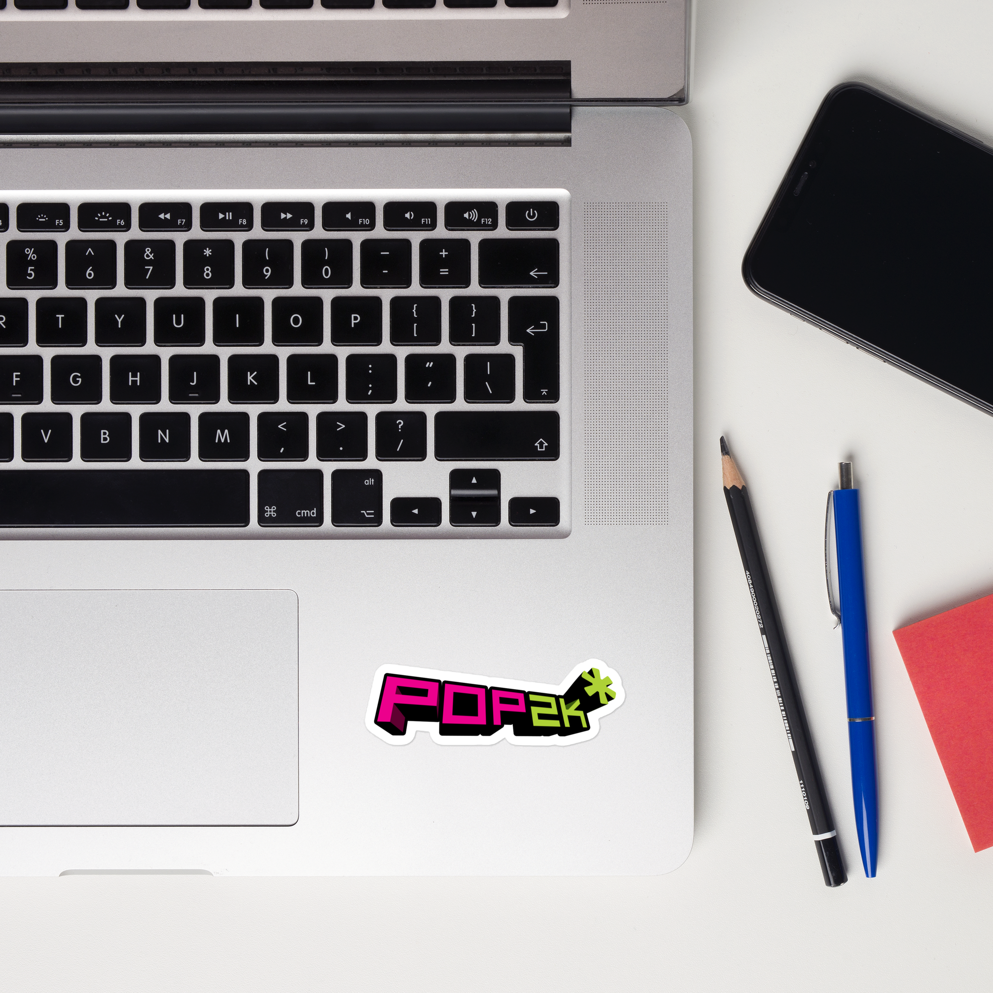 A laptop keyboard displaying a colorful 'POP2K' sticker on the right side of the trackpad