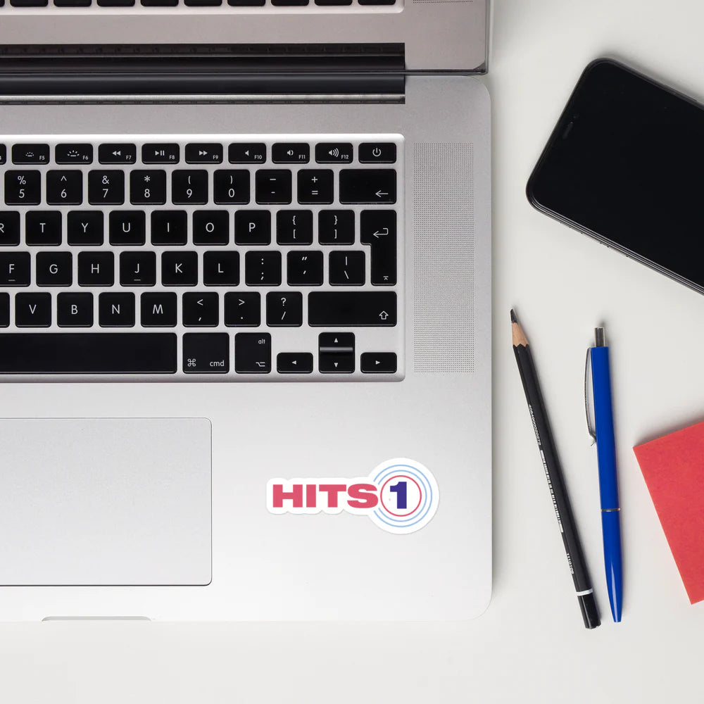 'Hits 1' sticker on laptop computer with pencil and pen beside computer.