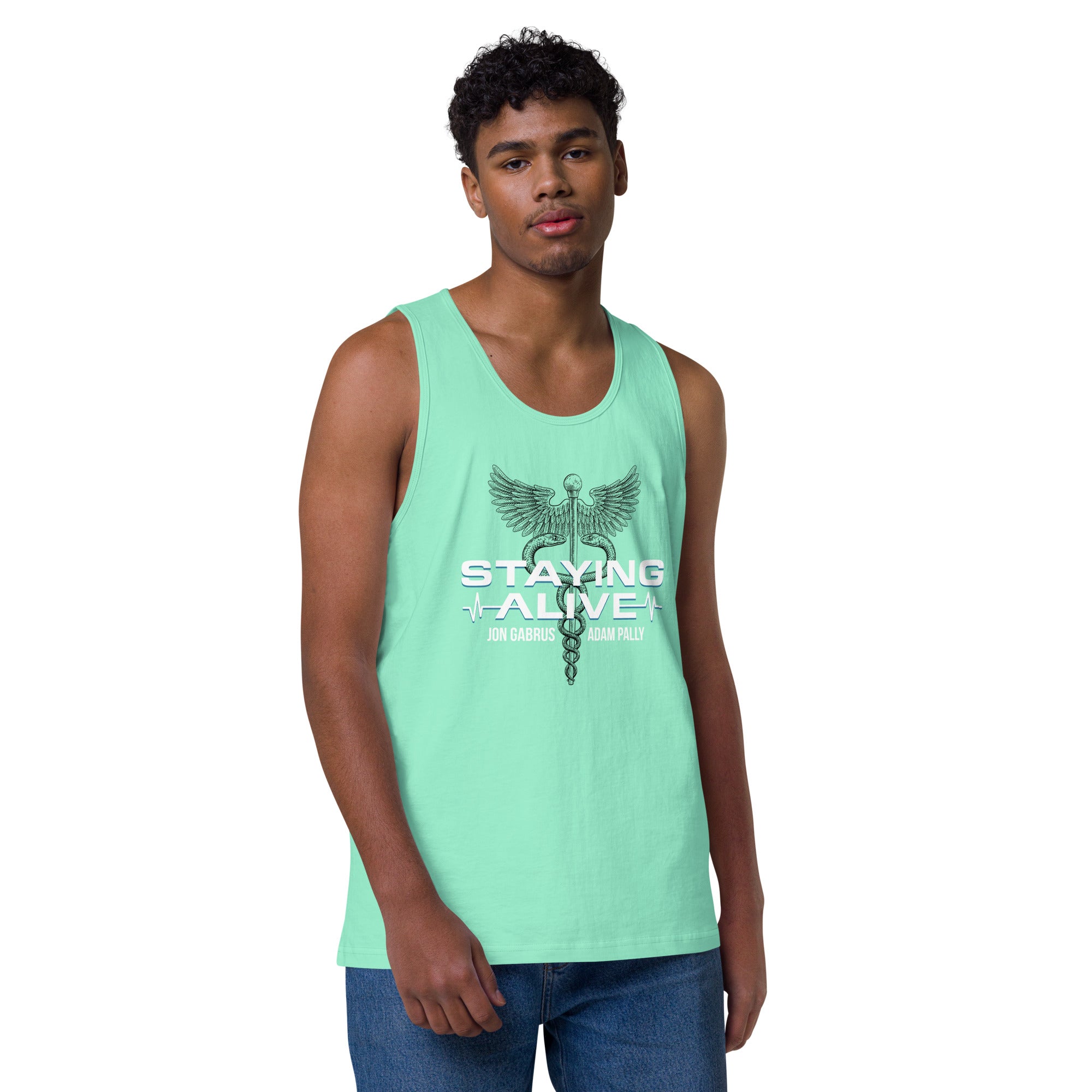 A person wearing a mint green tank top and jeans stands against a plain white background. The front of the tank features a caduceus emblem—a symbol of medical care with wings and entwined snakes—above bold white text that reads 'STAYING ALIVE', with teal heartbeat lines and the names 'JON GABRUS' and 'ADAM PALLY' printed below.