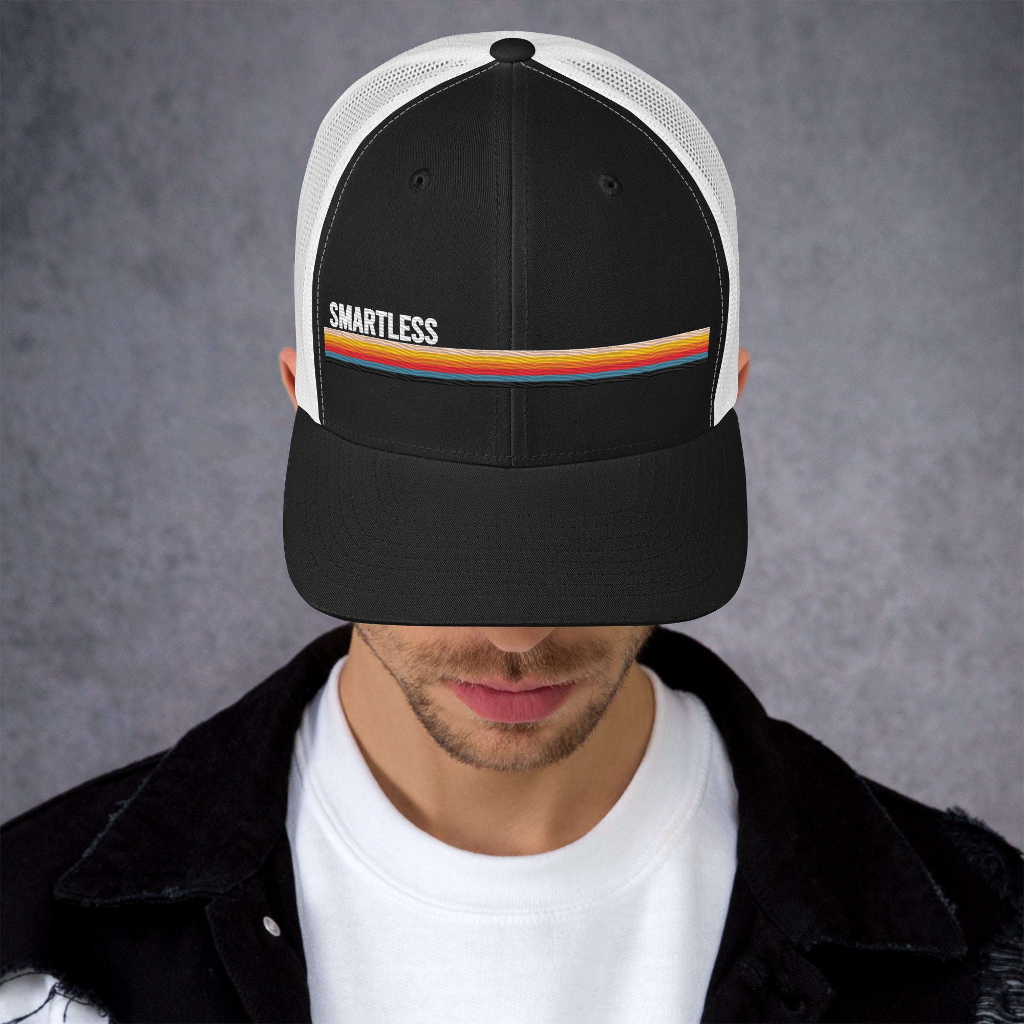 A person wearing a black and white baseball cap with the word 'SMARTLESS' and a colorful stripe across the front.