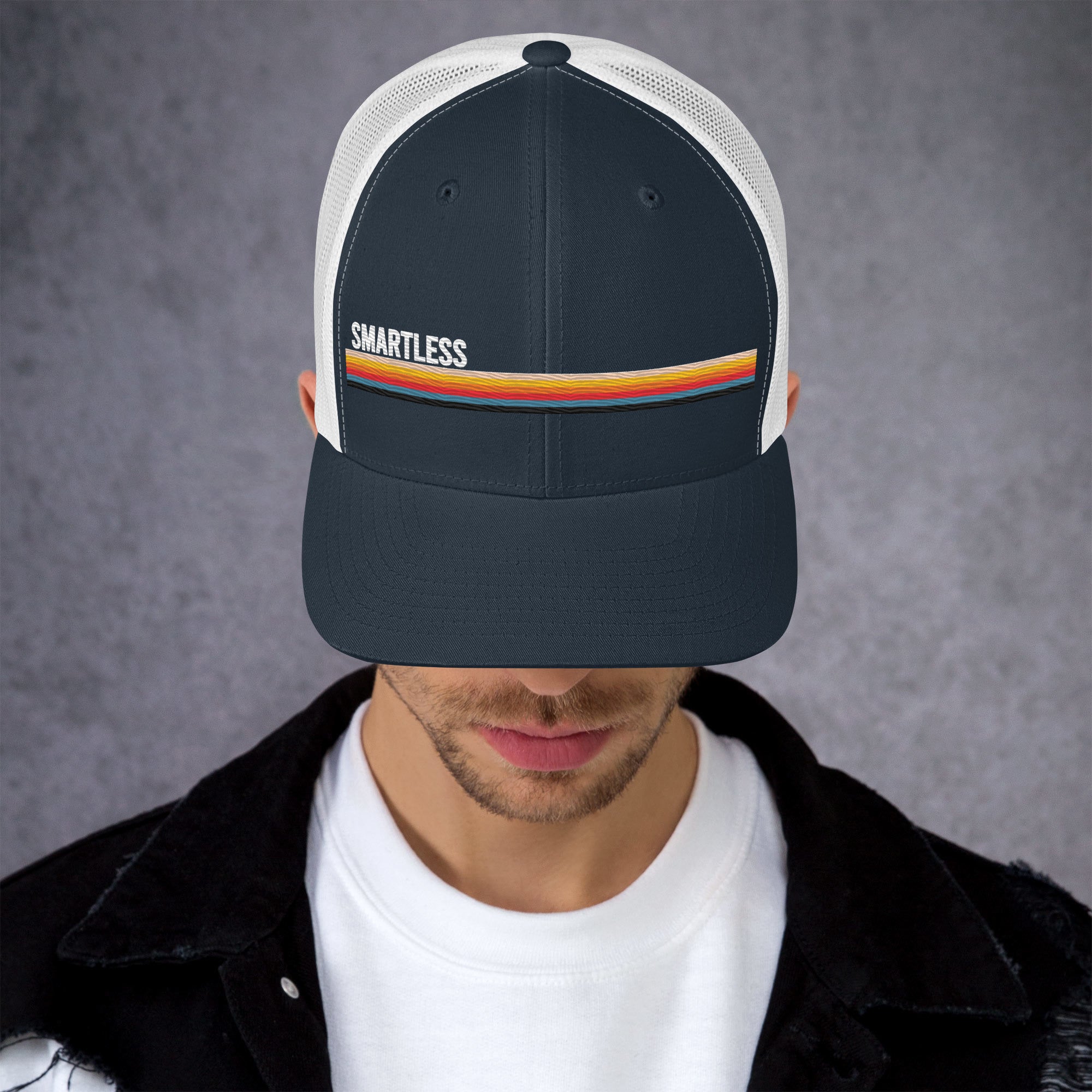 A person wearing a navy cap with the word 'SMARTLESS' and colorful stripes.