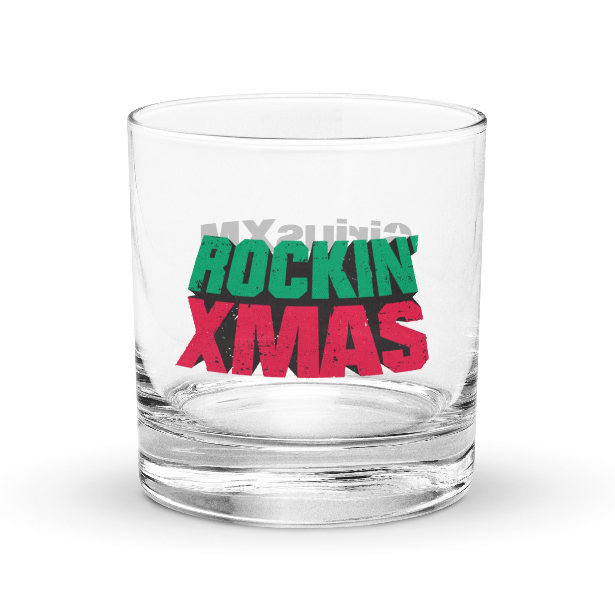 Clear rocks glass featuring the phrase ‘ROCKIN’ XMAS’ in bold distressed green and red letters on the front; the standalone ‘SiriusXM’ logo printed on the back of the glass is faintly visible through the transparent surface.