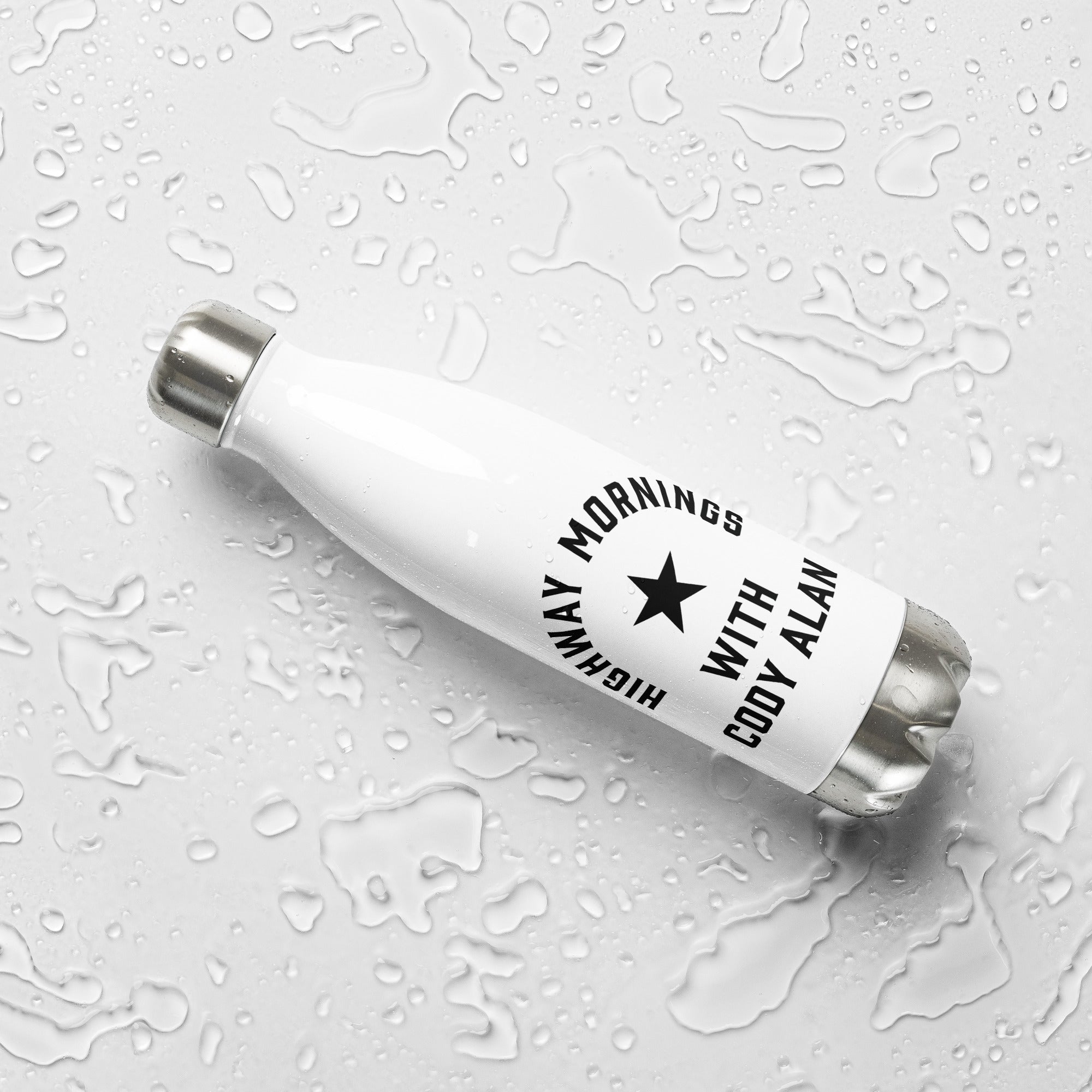 A white stainless steel water bottle with black 'HIGHWAY MORNINGS WITH CODY ALAN' text and star graphic, lying on its side on a white surface covered in water droplets.