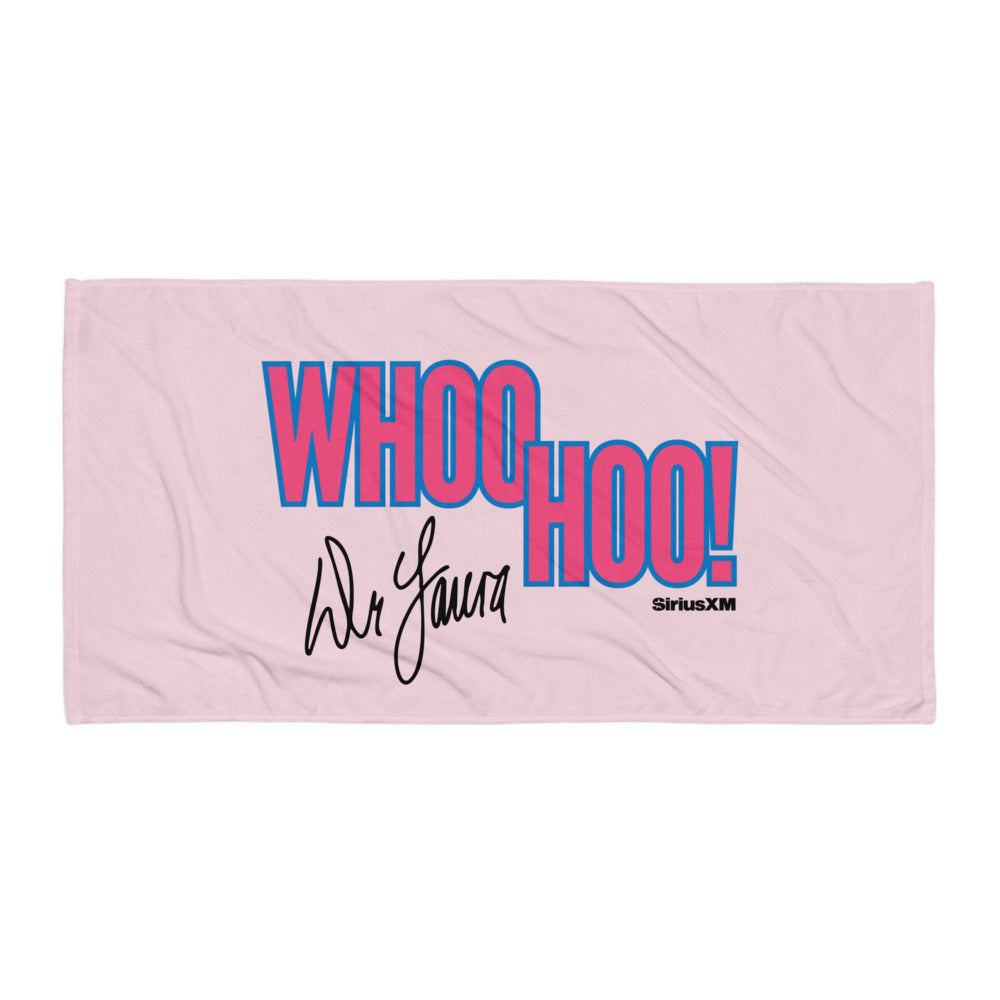A flat lay of a large pink beach towel featuring the phrase ‘WHOO HOO!’ in oversized blue and pink block letters and ‘Dr. Laura’ in black cursive, with a small ‘SiriusXM’ logo in the corner.