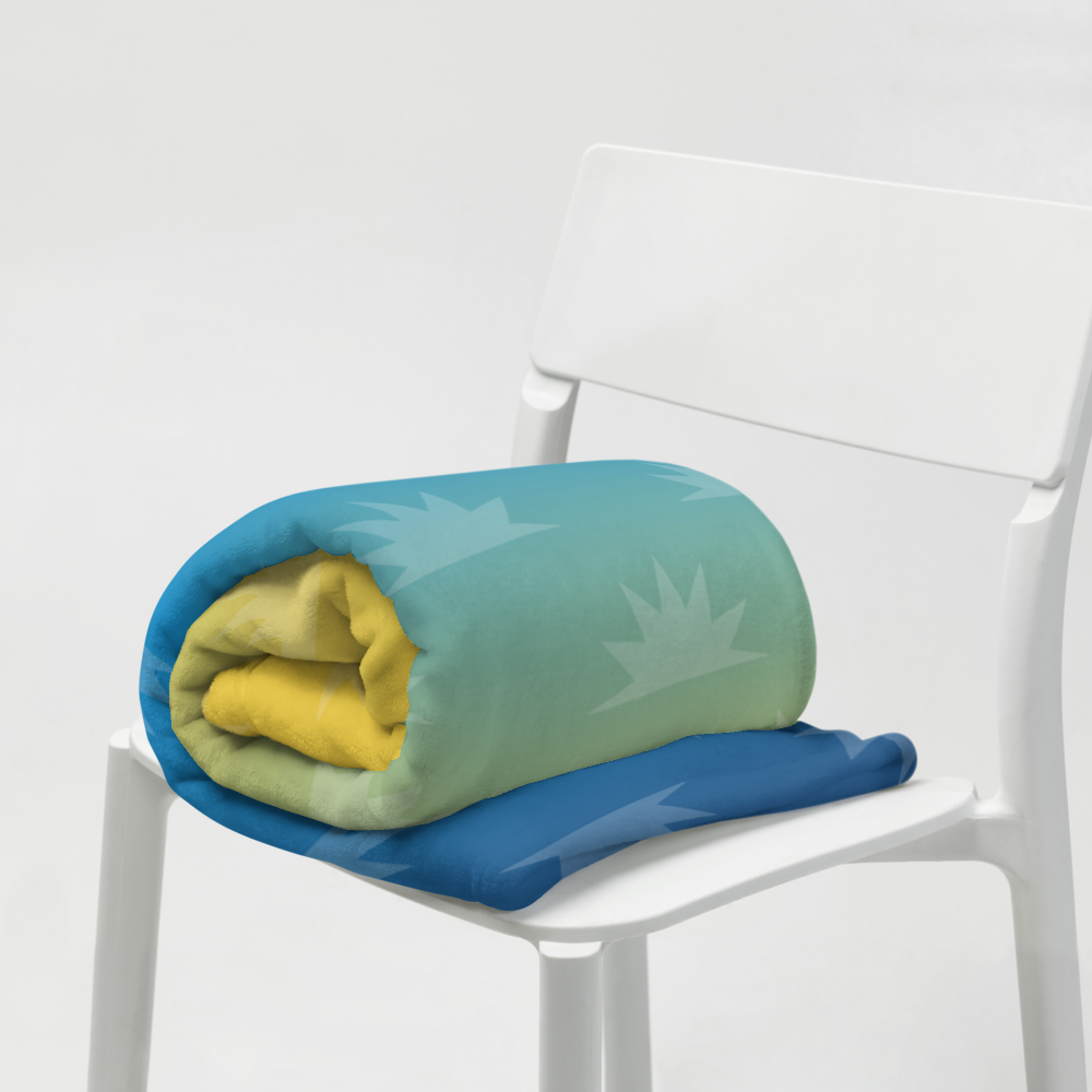 Folded blanket in shades of green, yellow, and blue, displayed on a white chair.