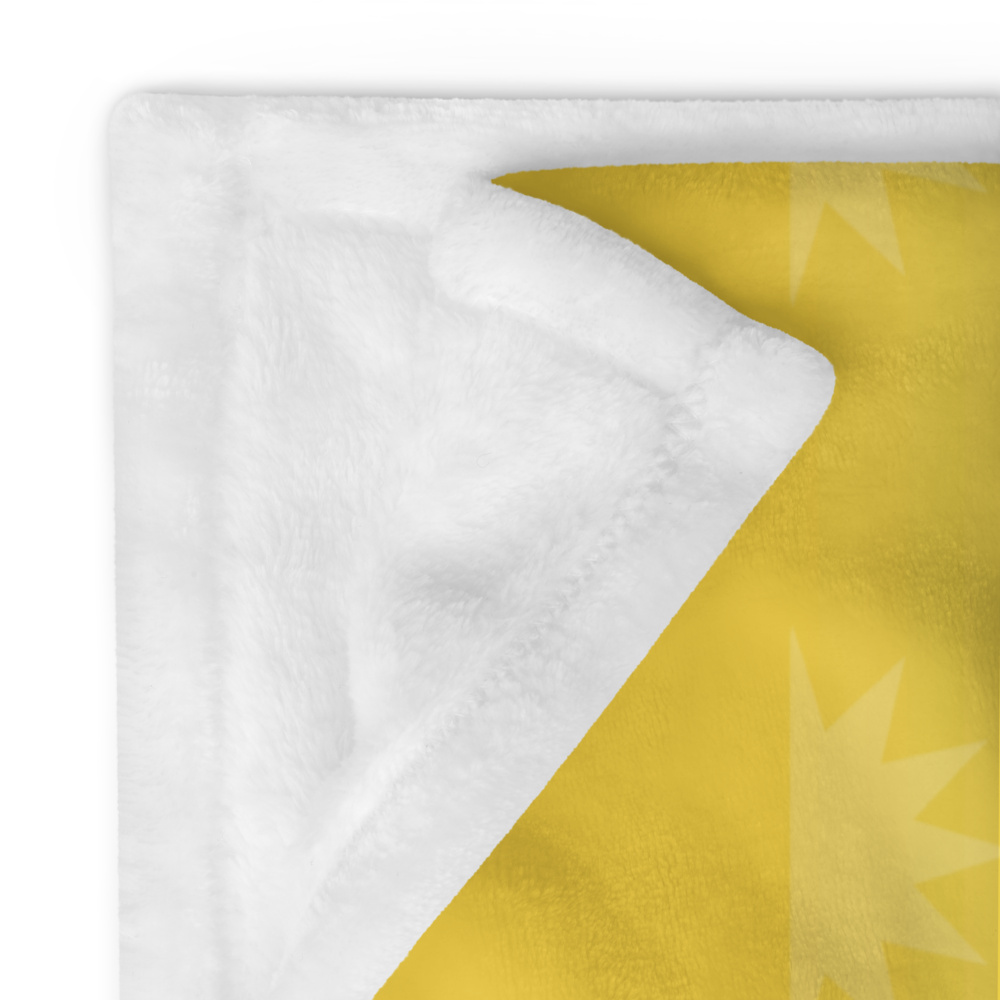 A corner of a yellow blanket with a white, fluffy edge, featuring a star design on the yellow side.