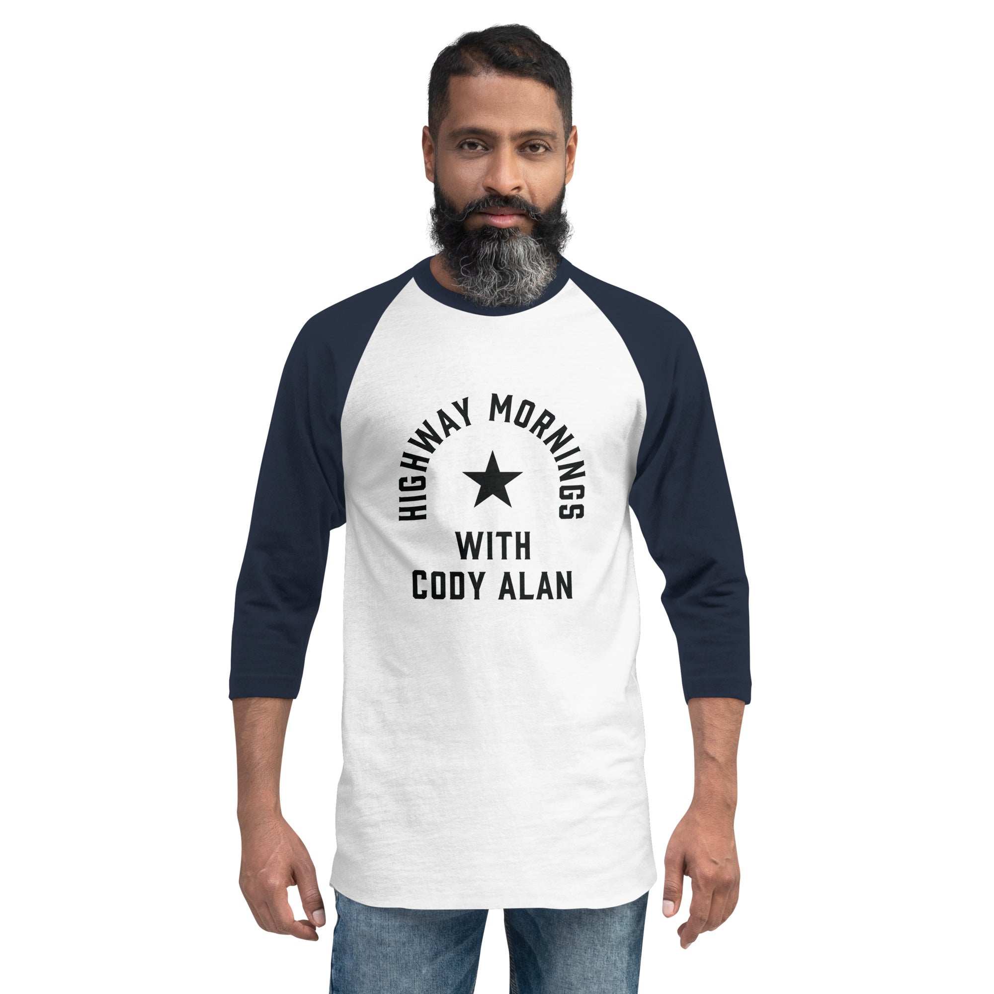 A man wears a white raglan shirt with navy sleeves displaying the text 'HIGHWAY MORNINGS WITH CODY ALAN' in black around a black star graphic on the front.