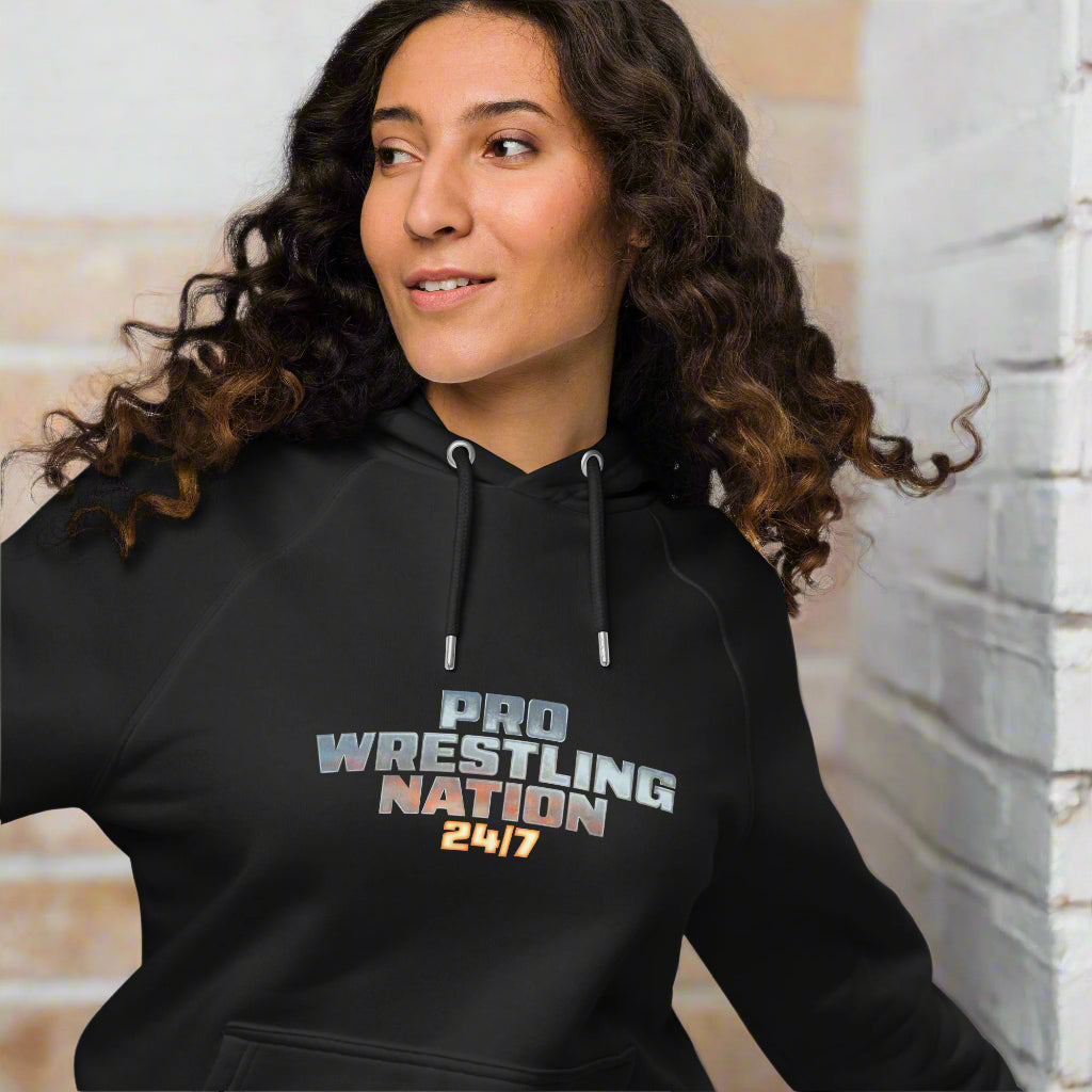 Close-up of a woman wearing a black hoodie with the 'Pro Wrestling Nation 24/7' logo, showcasing the raglan sleeve detail and relaxed fit.