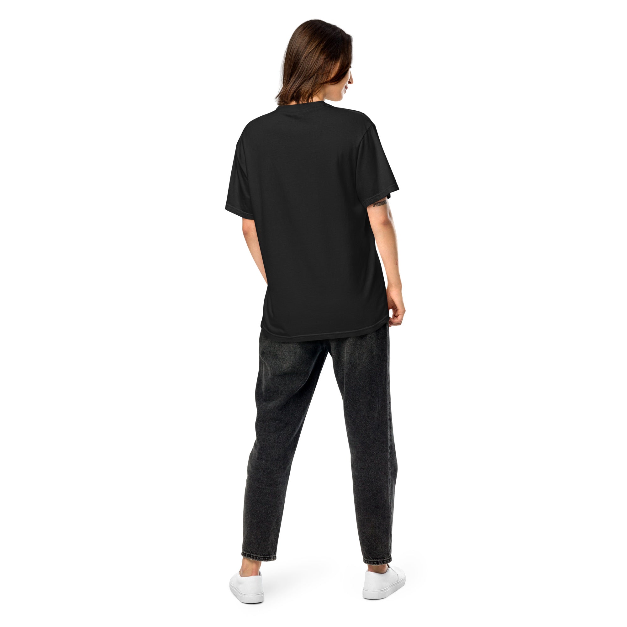 A woman shown from the back wearing a plain black short-sleeve T-shirt with relaxed-fit black jeans and white sneakers. The shirt’s back has no visible design or text.