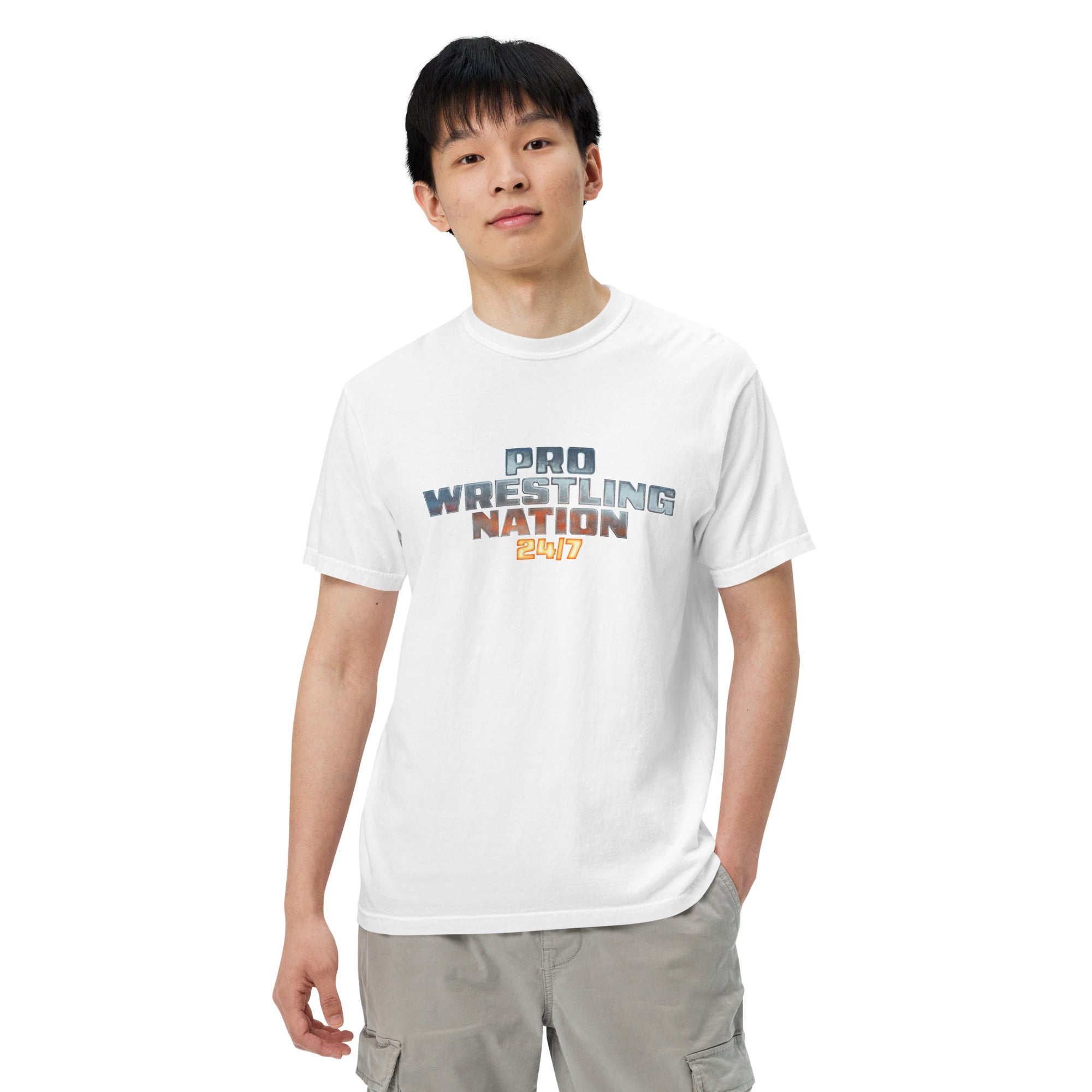 Front view of a male model wearing a white 'Pro Wrestling Nation 24/7' T-shirt with a relaxed fit and hands in pockets.
