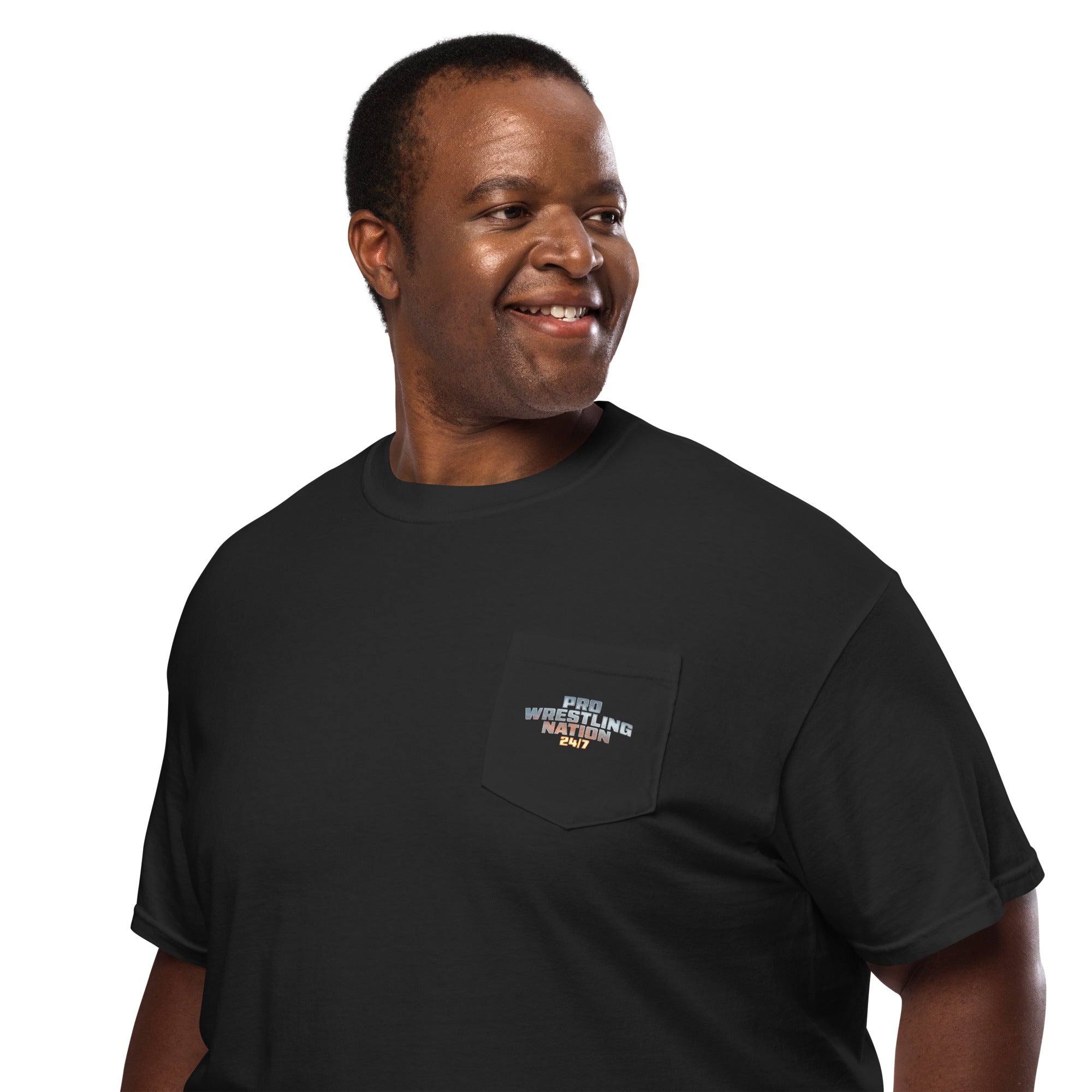 A man smiling while wearing a black pocket t-shirt featuring the 'Pro Wrestling Nation 24/7' logo on the front pocket.