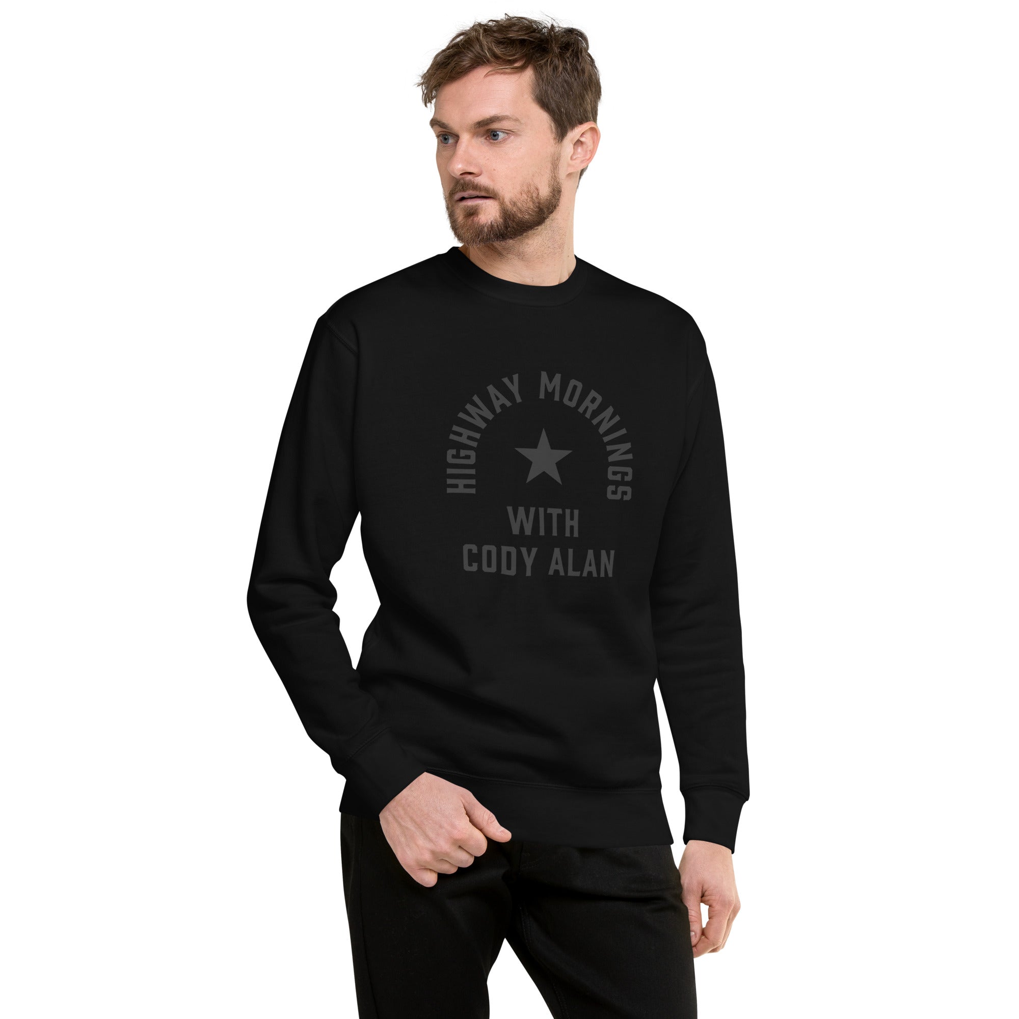 A man shown in a front view wearing a black crewneck sweatshirt. The front features a black star and the text 'HIGHWAY MORNINGS WITH CODY ALAN' printed in black for a subtle monochrome effect.