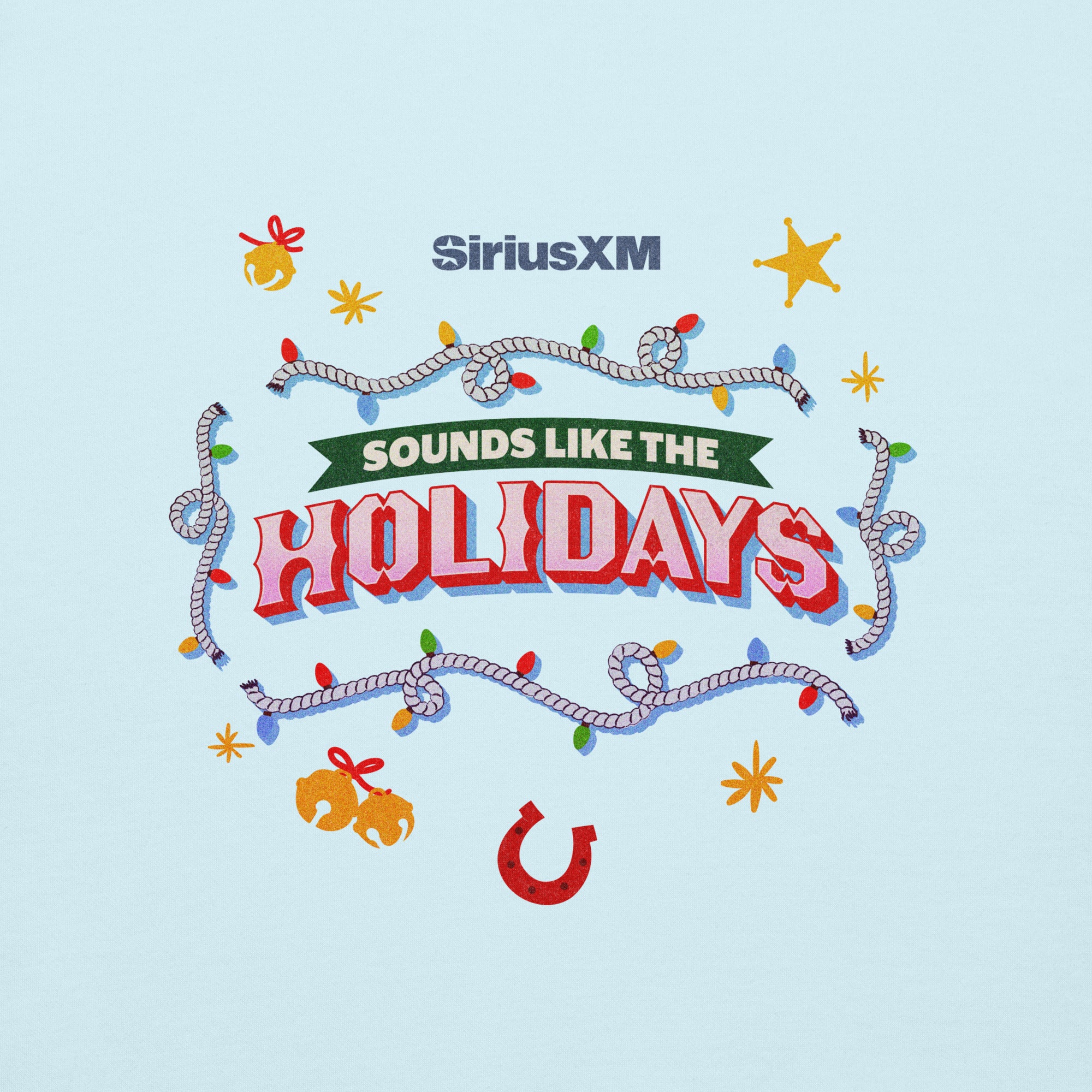 Close-up of the front design on a light blue sweatshirt showing the white ‘SiriusXM’ logo and the colorful text ‘Sounds like the HOLIDAYS,’ surrounded by holiday-themed illustrations including lights, a rope border, bells, stars, and a red horseshoe.